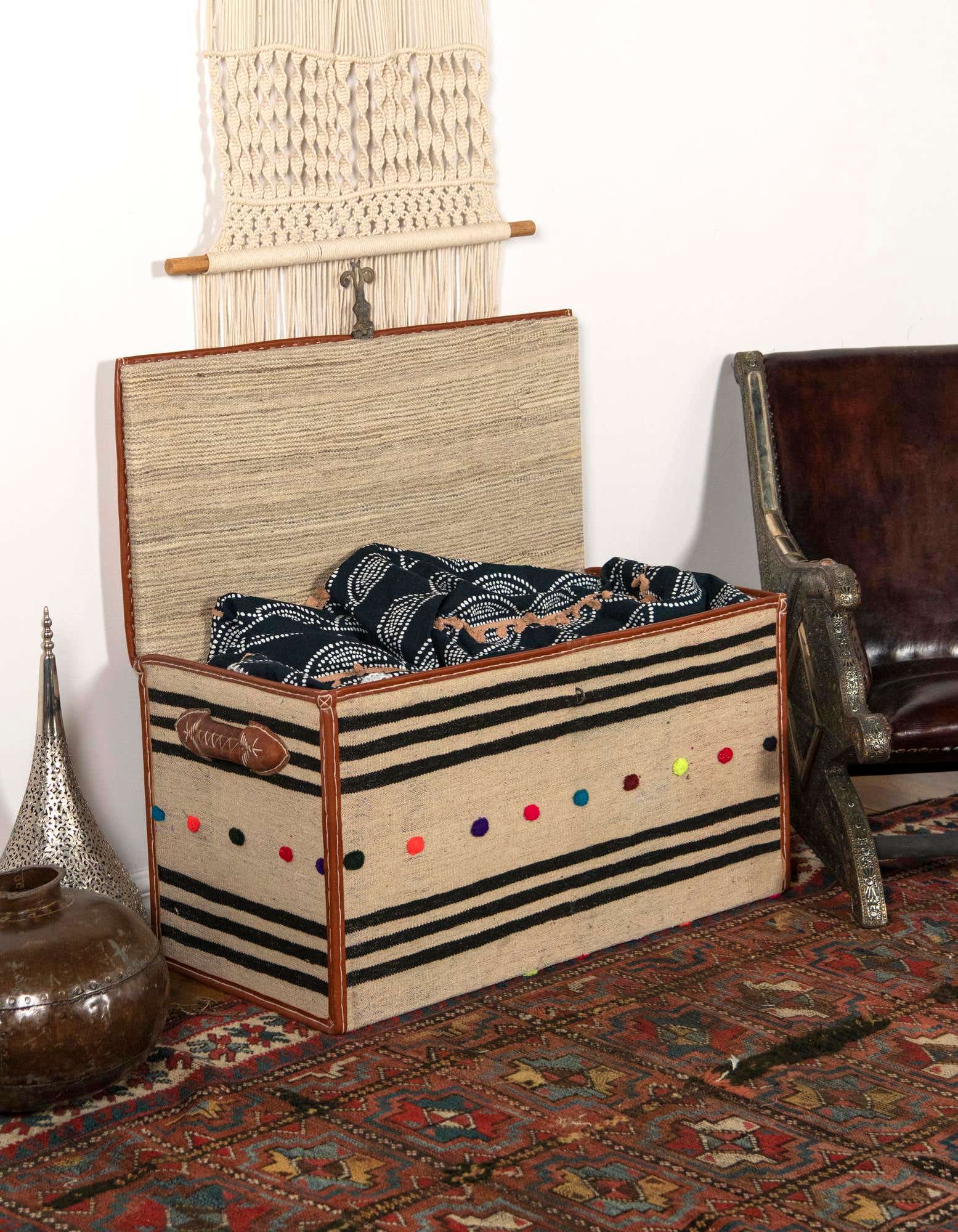 A 2x3 rectangular rug with a traditional Oriental pattern in shades of red, blue, and cream, under a decorative storage chest.