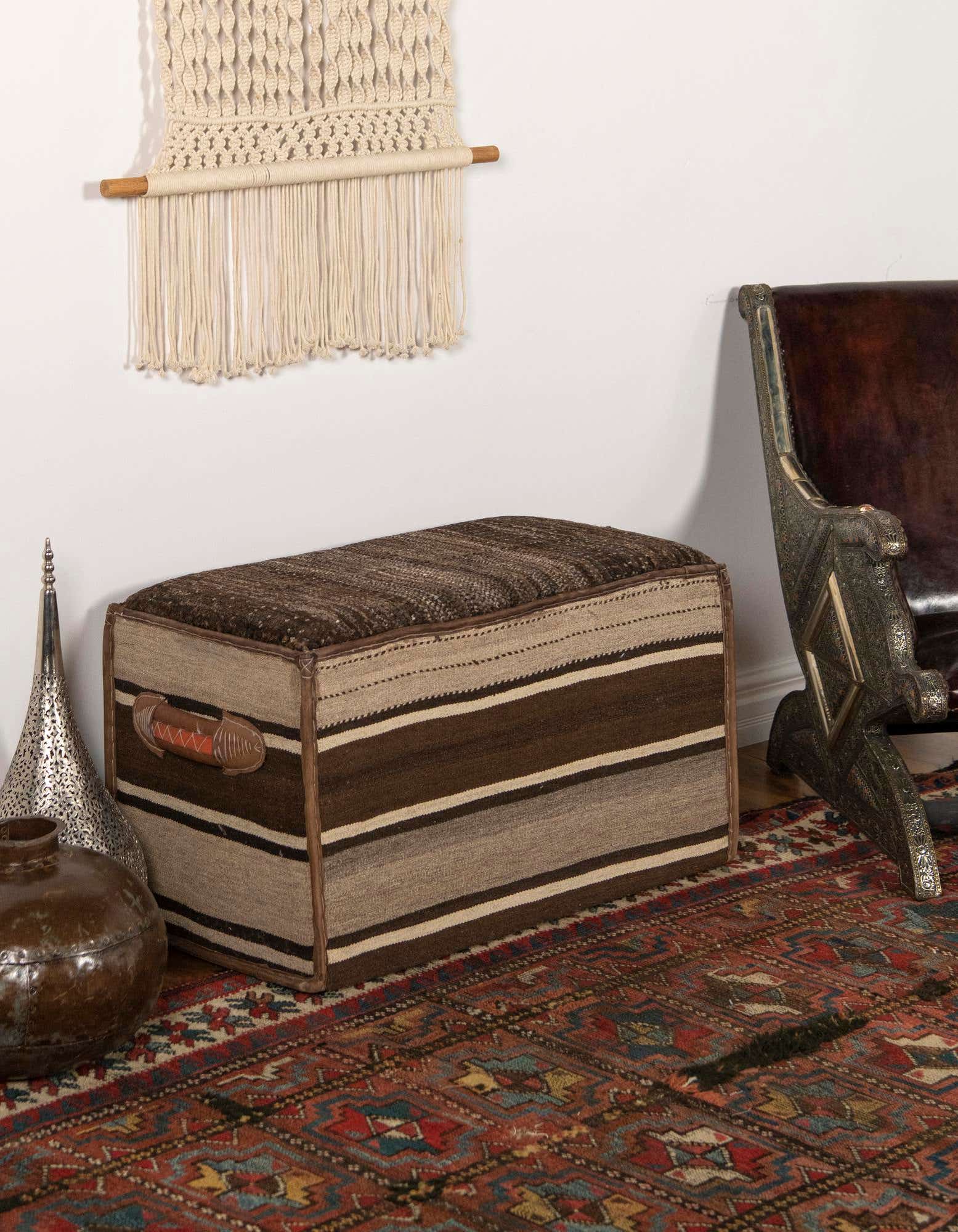 A 2x3 rectangular rug with a distressed Oriental pattern in shades of red, blue, and gold, under a striped ottoman.