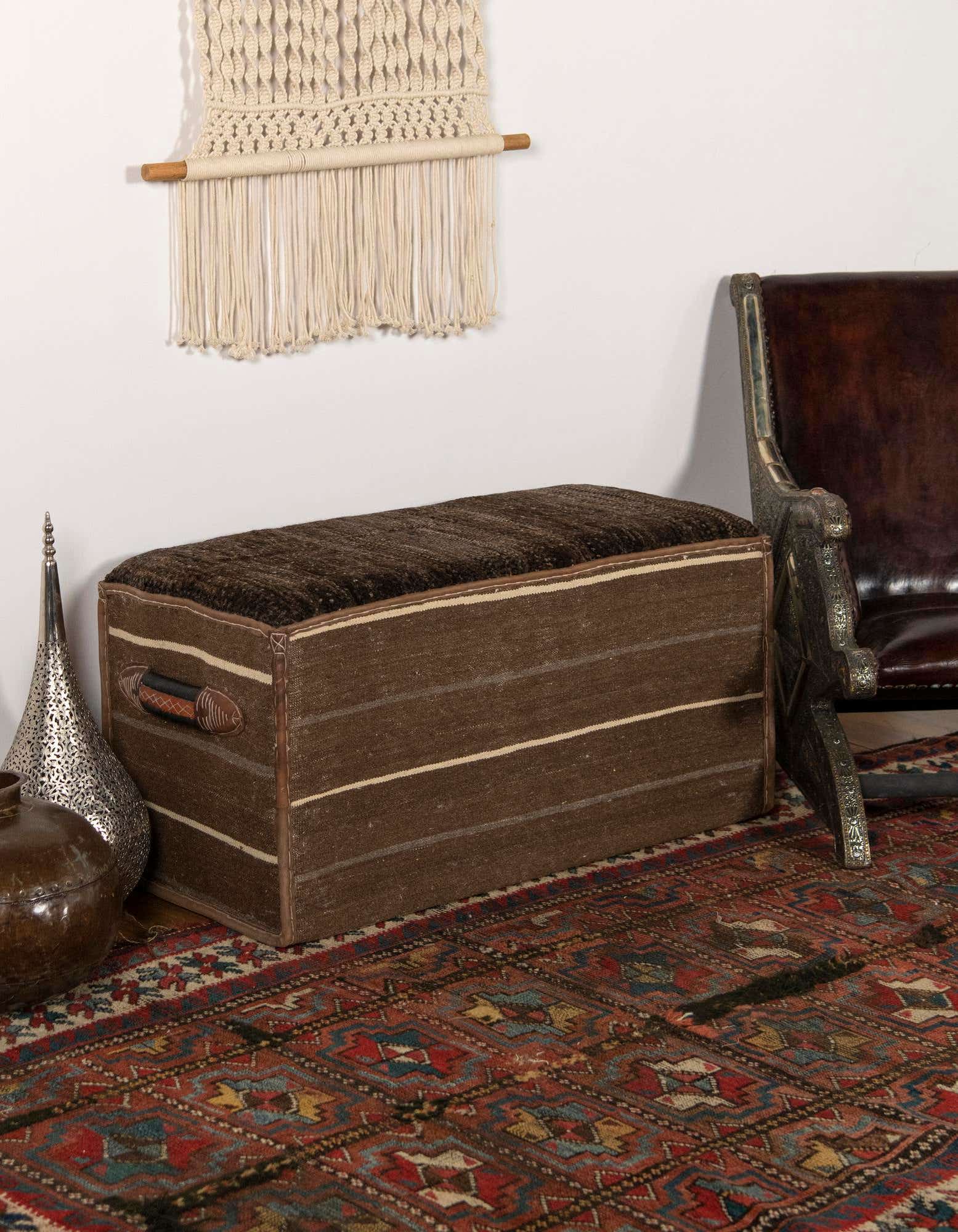 A 2x3 rectangular brown and tan traditional rug with an oriental pattern under a wooden storage bench.