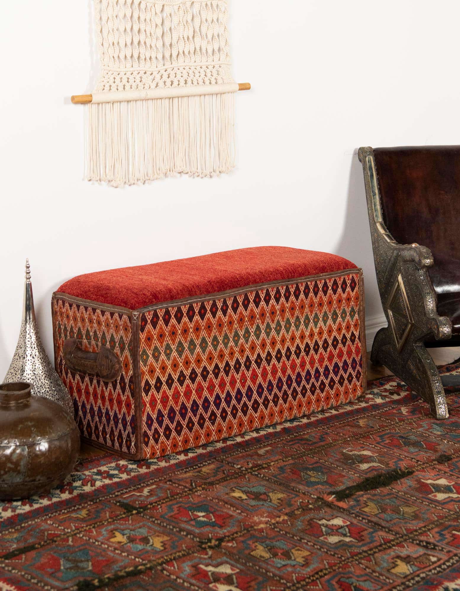 A 2x3 rectangular orange and red traditional oriental rug with intricate patterns, complementing a patterned storage bench in a living room.