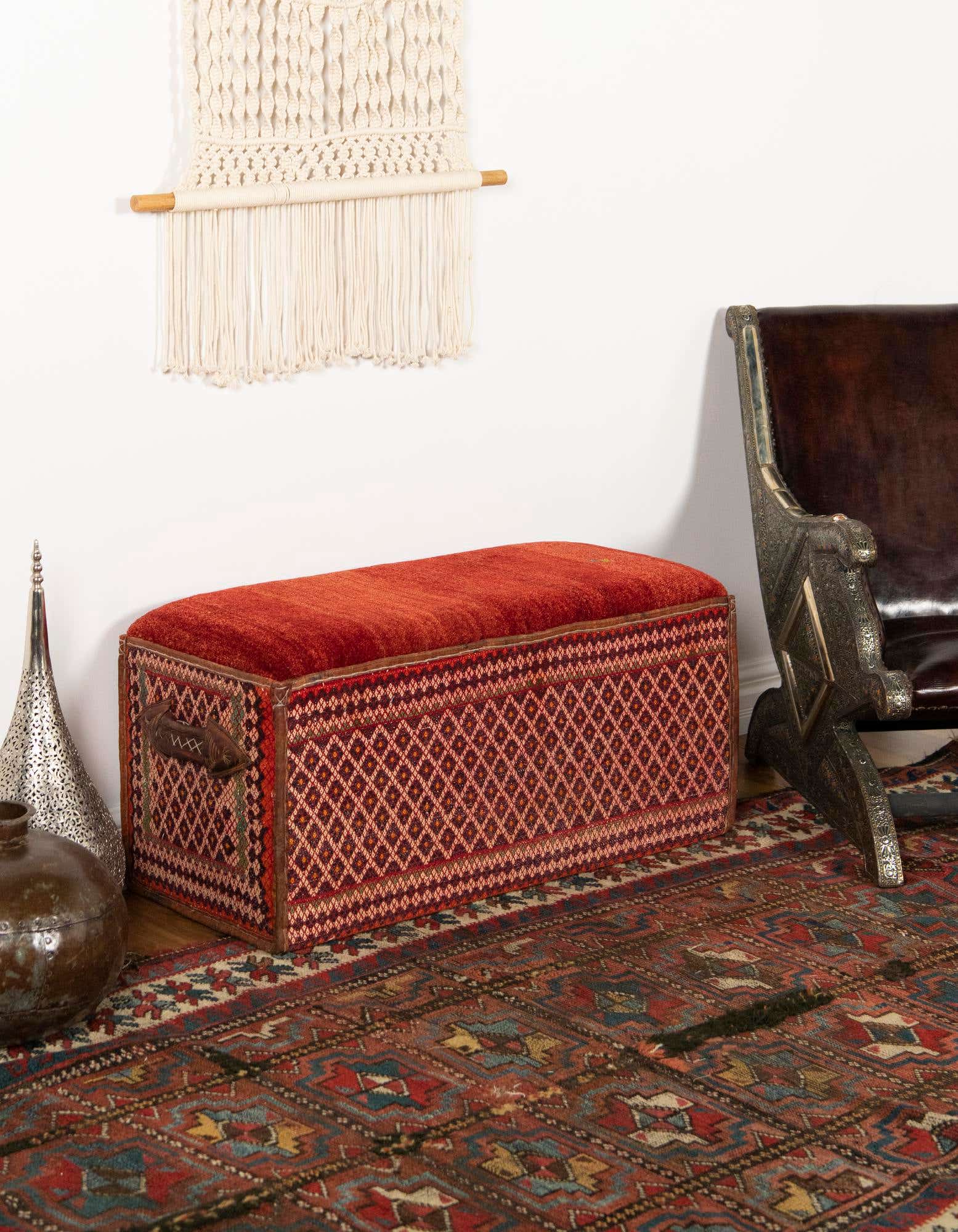 A 2x3 rectangular orange and red Oriental rug with intricate patterns, laid on a wooden floor in an entryway.