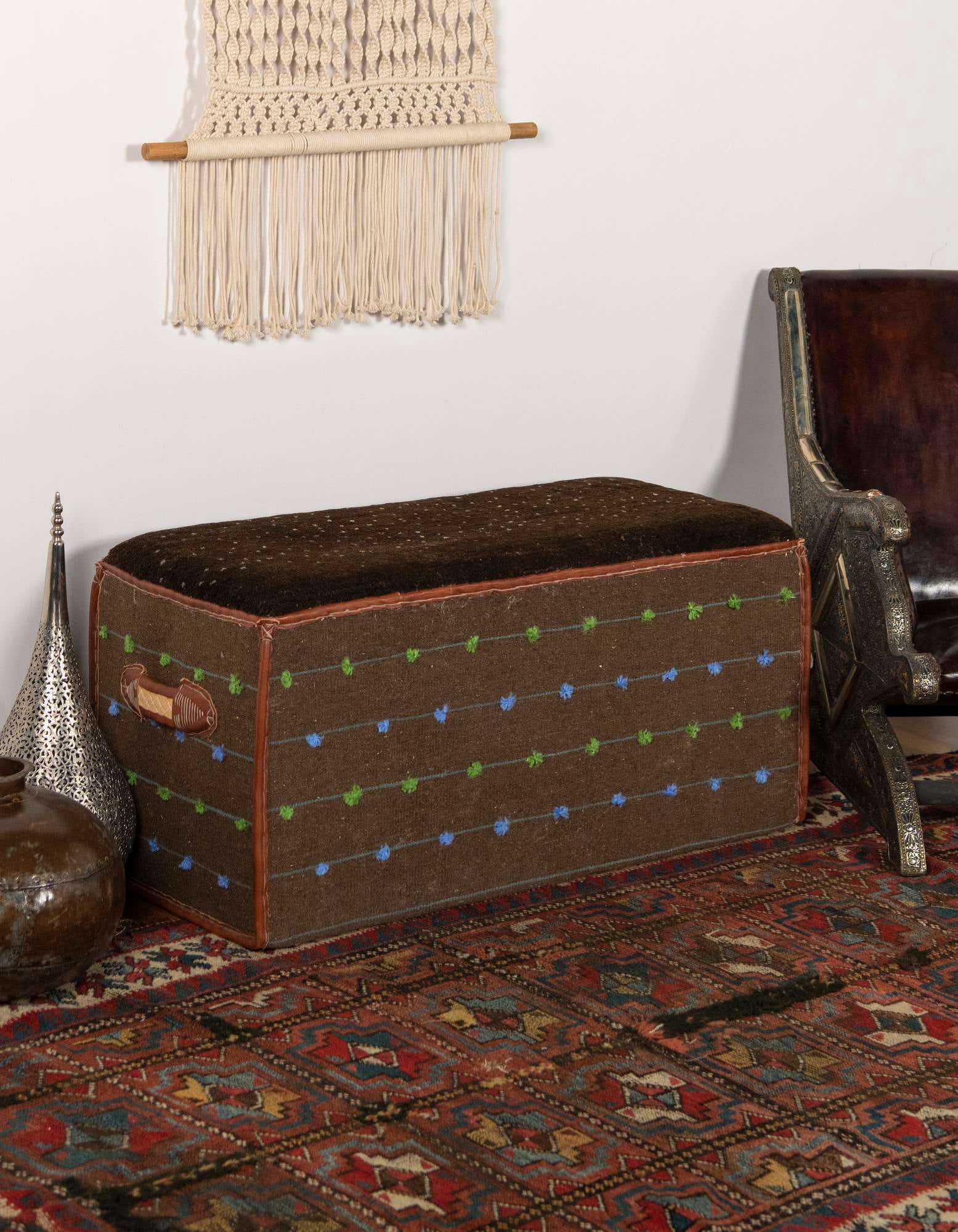 A 2x3 rectangular brown traditional rug with intricate red, blue, and tan oriental patterns, styled under a brown ottoman.