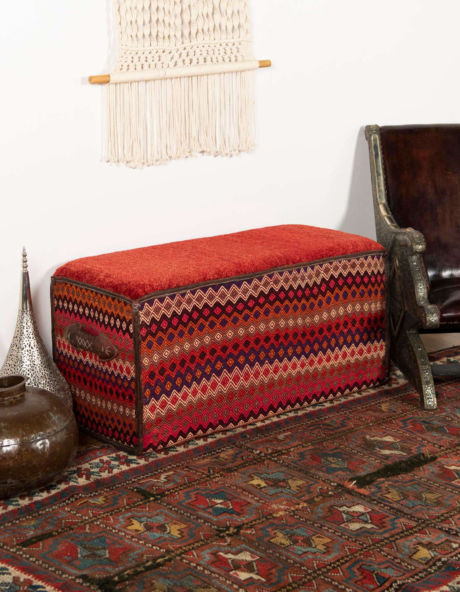 A 2x3 rectangular rug with a modern stripe pattern in oranges and reds, styled in an entryway under a decorative storage bench.
