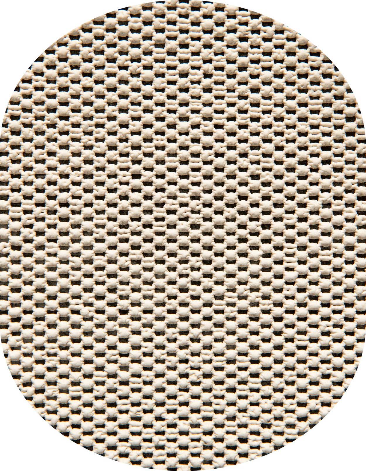 Close-up of a white textured rug pad with a grid pattern of small raised bumps on a dark background, providing non-slip grip.