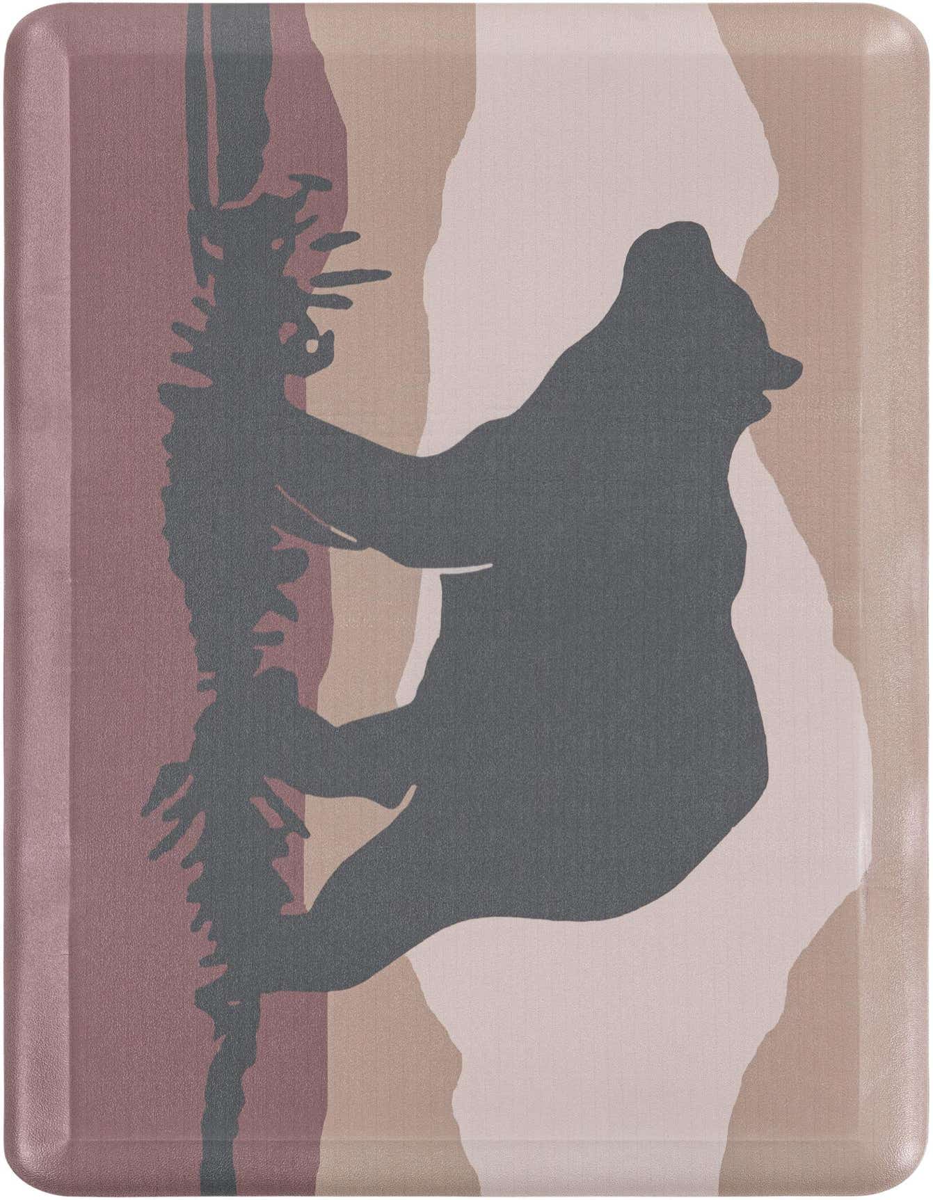 A rectangular multi-colored comfort mat featuring a dark gray silhouette of a bear climbing a tree against a background of abstract pink, beige, and white shapes.