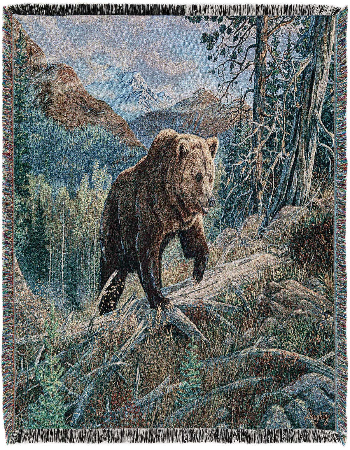 A multi-colored rectangular throw blanket featuring a brown bear walking through a forest with mountains in the background.
