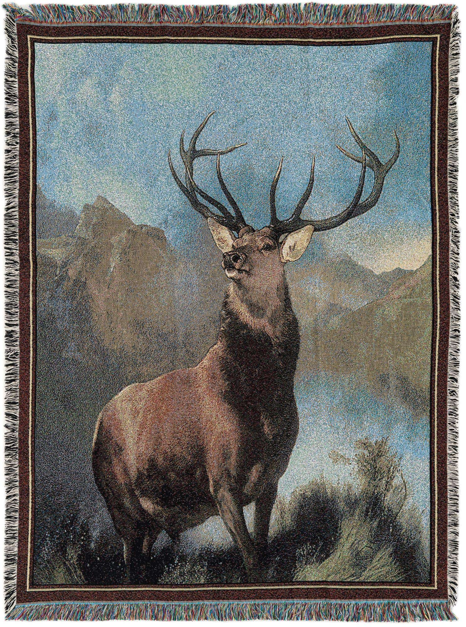 A rectangular 4x6 multi-colored rug featuring a majestic stag with large antlers against a mountain and blue sky backdrop, bordered by brown and white stripes with fringed edges.