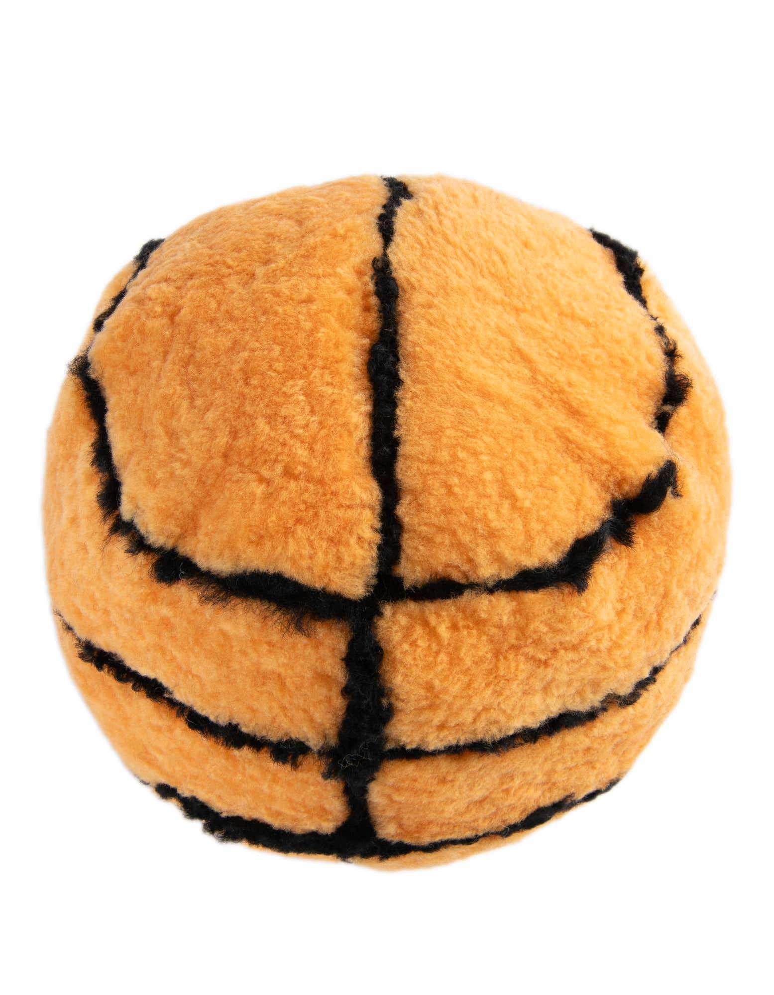 A soft, orange lambskin basketball-shaped pillow with black seam details, perfect for a sports-themed room.