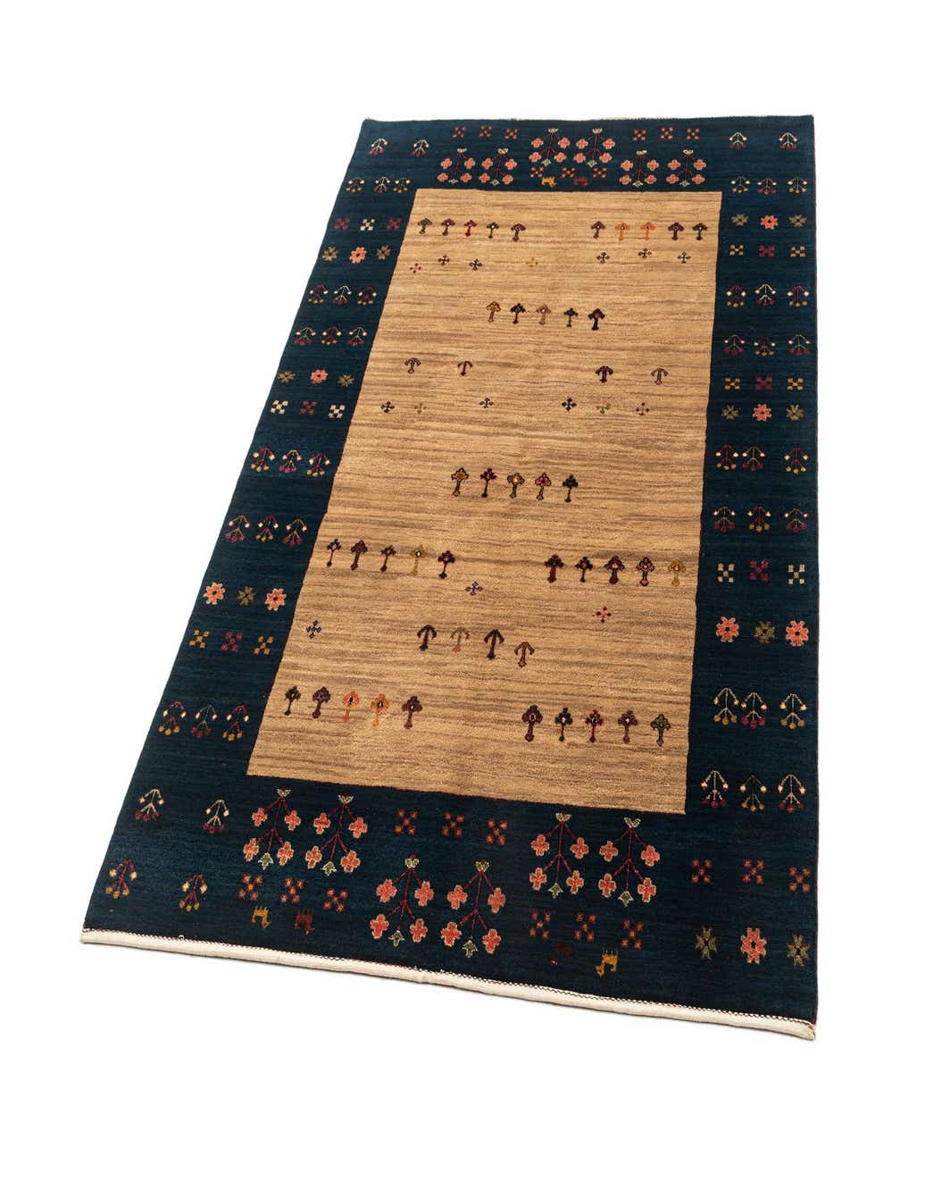 A 4x6 rectangular Gabbeh rug with a tan center field featuring small, stylized tree motifs, bordered by a dark blue band with floral and geometric patterns.