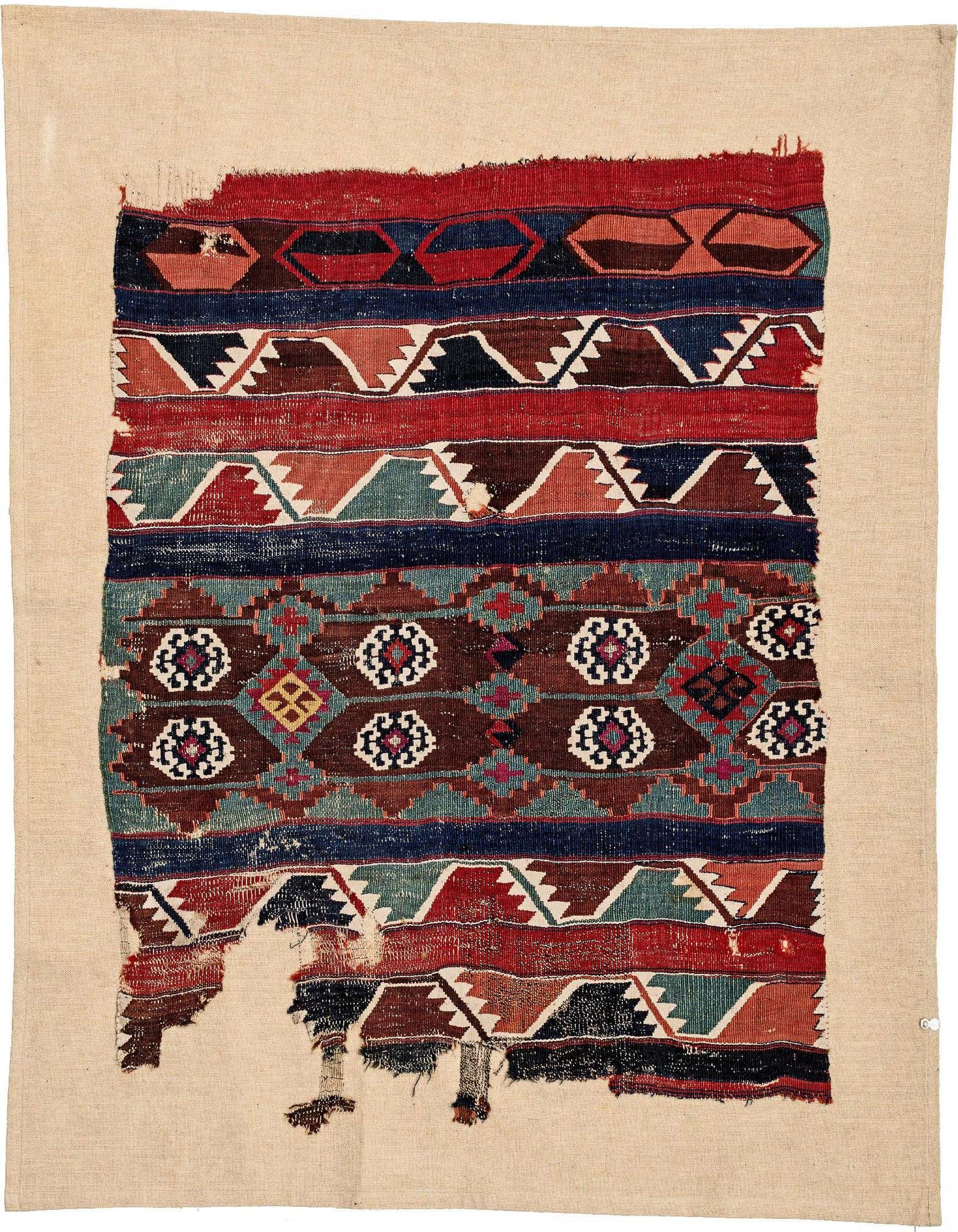 A rectangular 3x5 handmade wool rug with a distressed, multi-colored tribal pattern in browns, reds, blues, and creams.