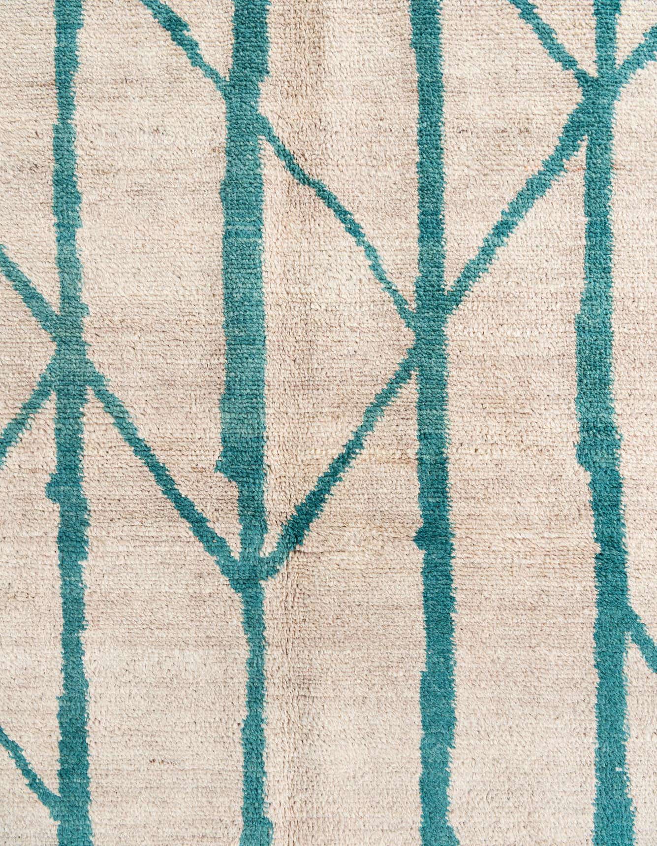 Close-up of a 6x9 rectangular shag rug with a cream background and a teal abstract tribal pattern.