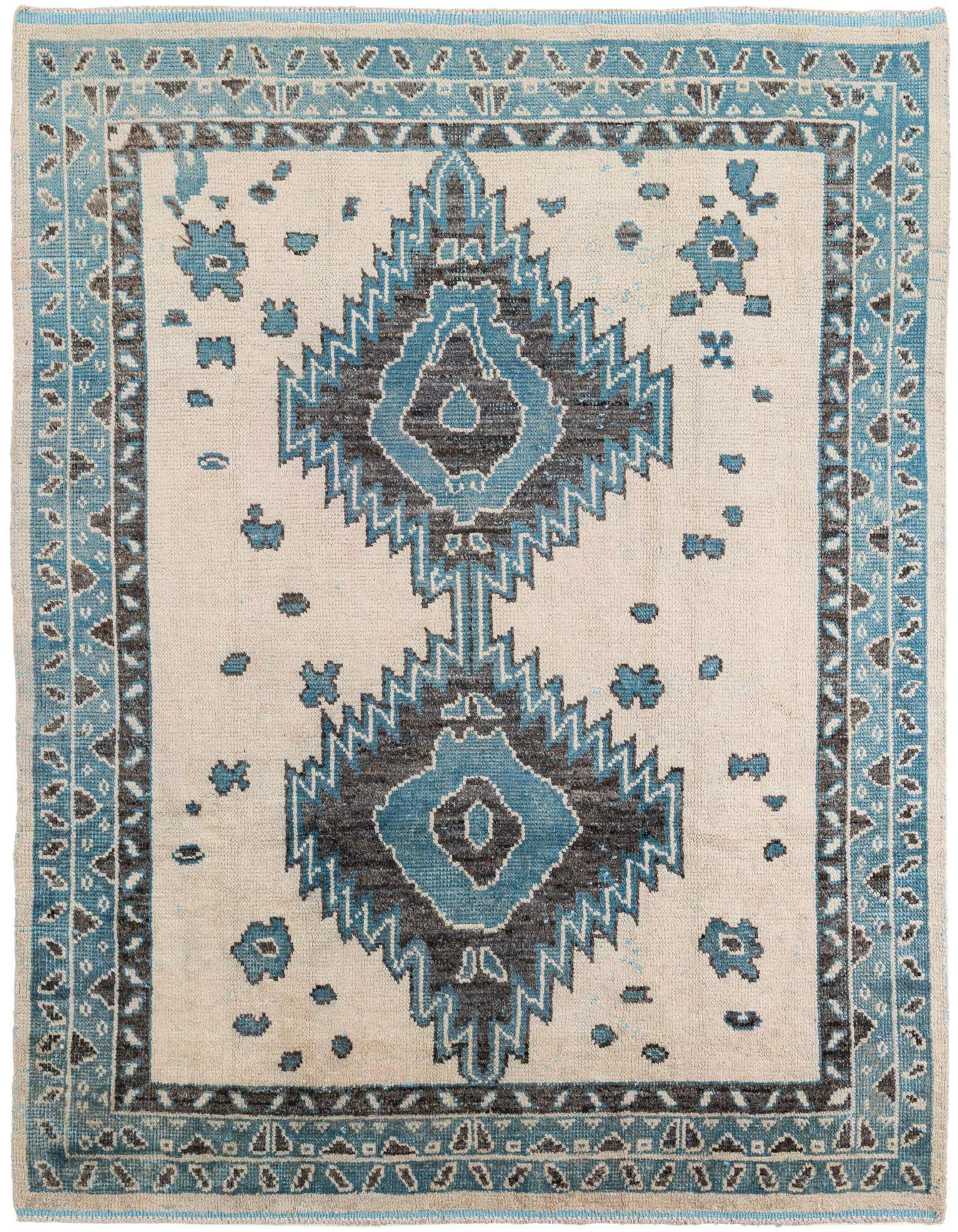 An 8x10 rectangular Moroccan shag rug with a central tribal medallion in blue and dark brown on an ivory background, framed by a blue and brown border.