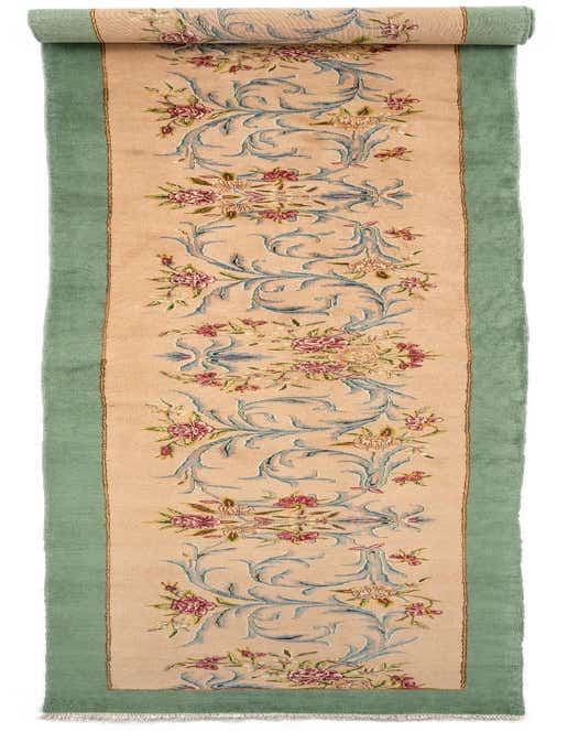 A 21 ft Kerman runner rug with a tan center, light green border, and intricate Persian floral patterns in blue, pink, and ivory.