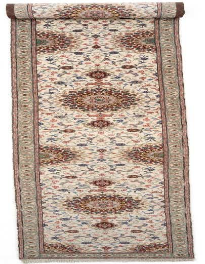 A 19 ft Tabriz runner rug with a cream background and intricate Persian floral patterns in brown, red, and blue.