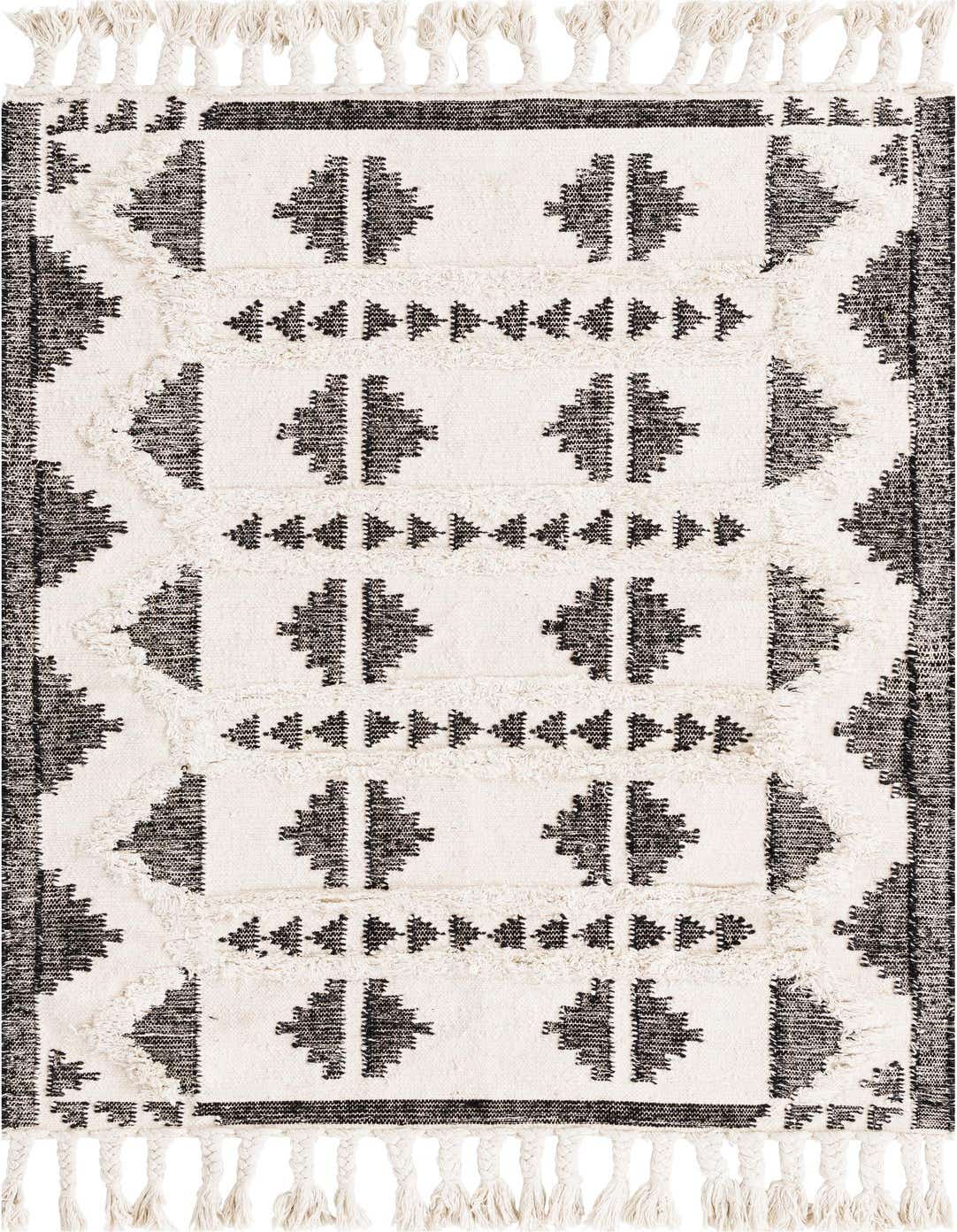 A 4x6 rectangular black and white tribal shag rug with geometric patterns and braided tassels, perfect for a modern living room.