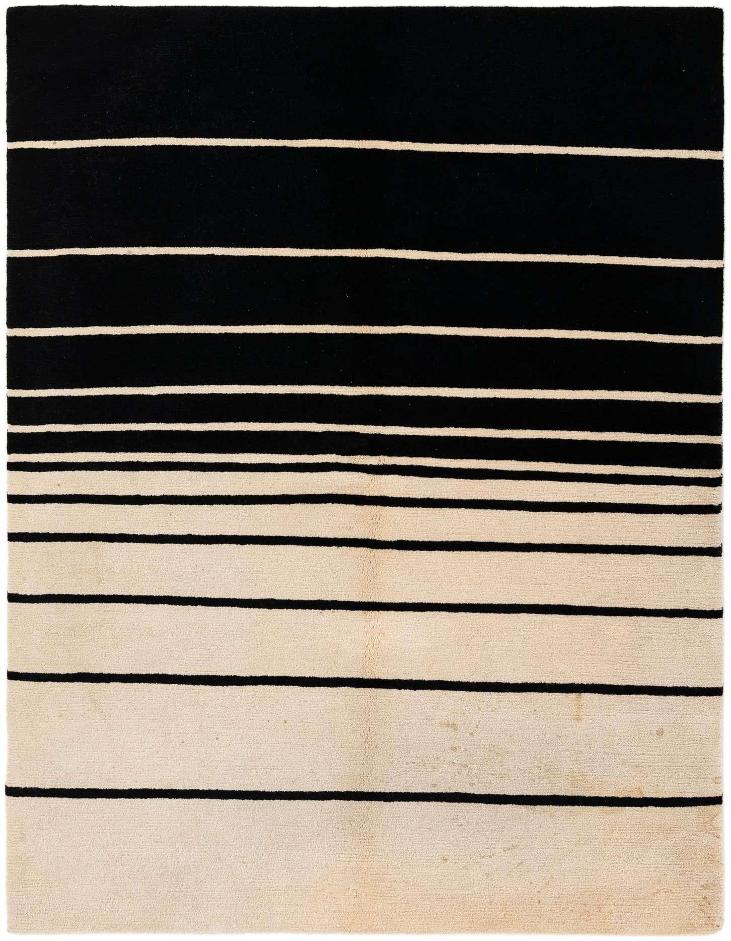A 5x8 rectangular black and ivory striped wool rug with varying stripe widths, ideal for a modern living room.