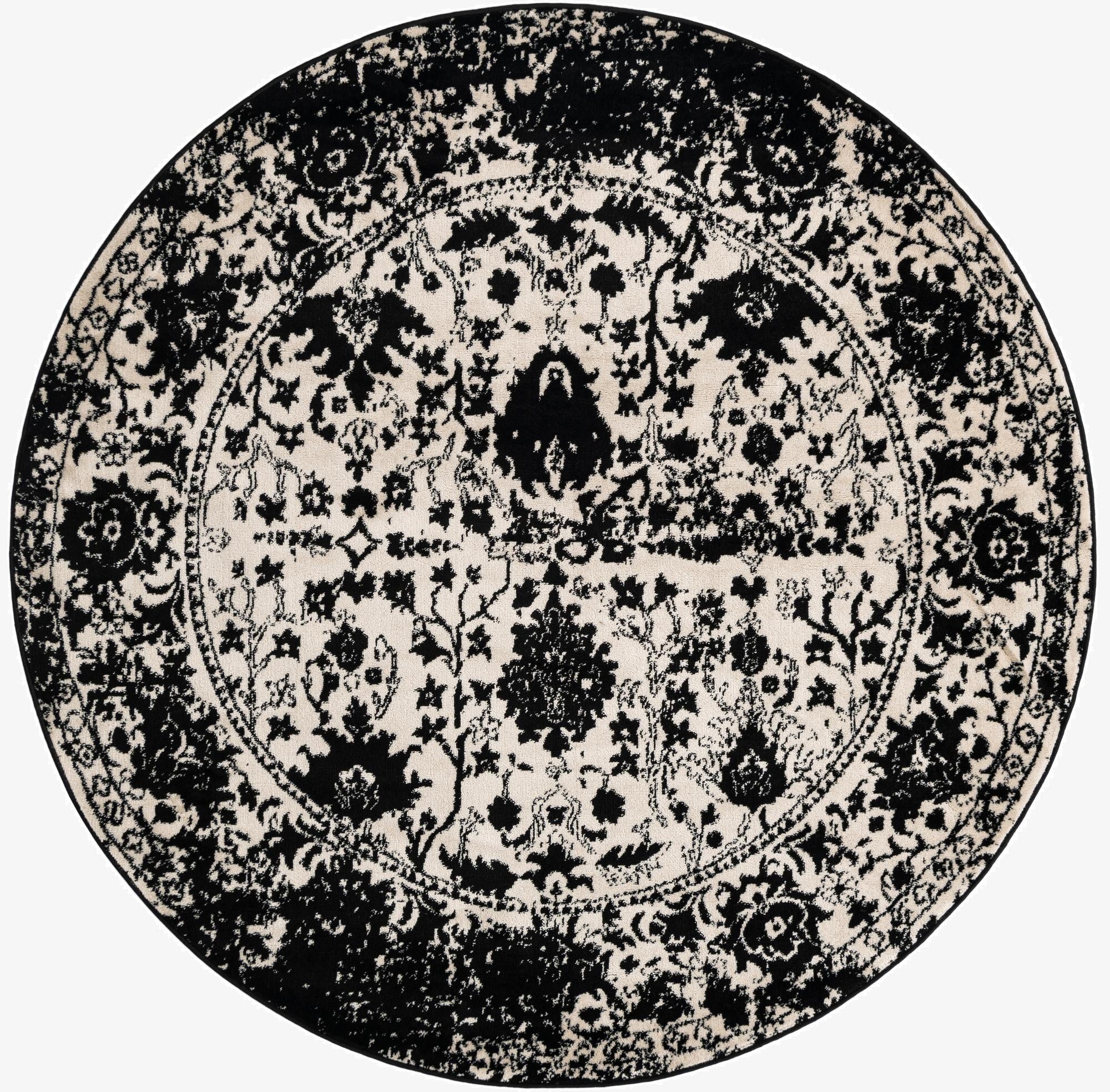 A 7' round black and white shabby-chic rug with a distressed floral medallion pattern.