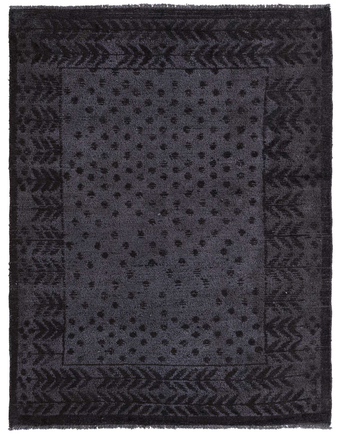 A 5x8 rectangular black wool rug with a modern abstract pattern of subtle polka dots and a geometric border.