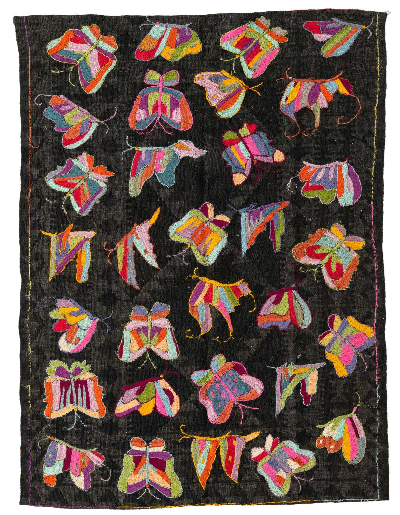 A 4x6 rectangular black wool flatweave rug with a vibrant, colorful butterfly and moth pattern, ideal for a living room.