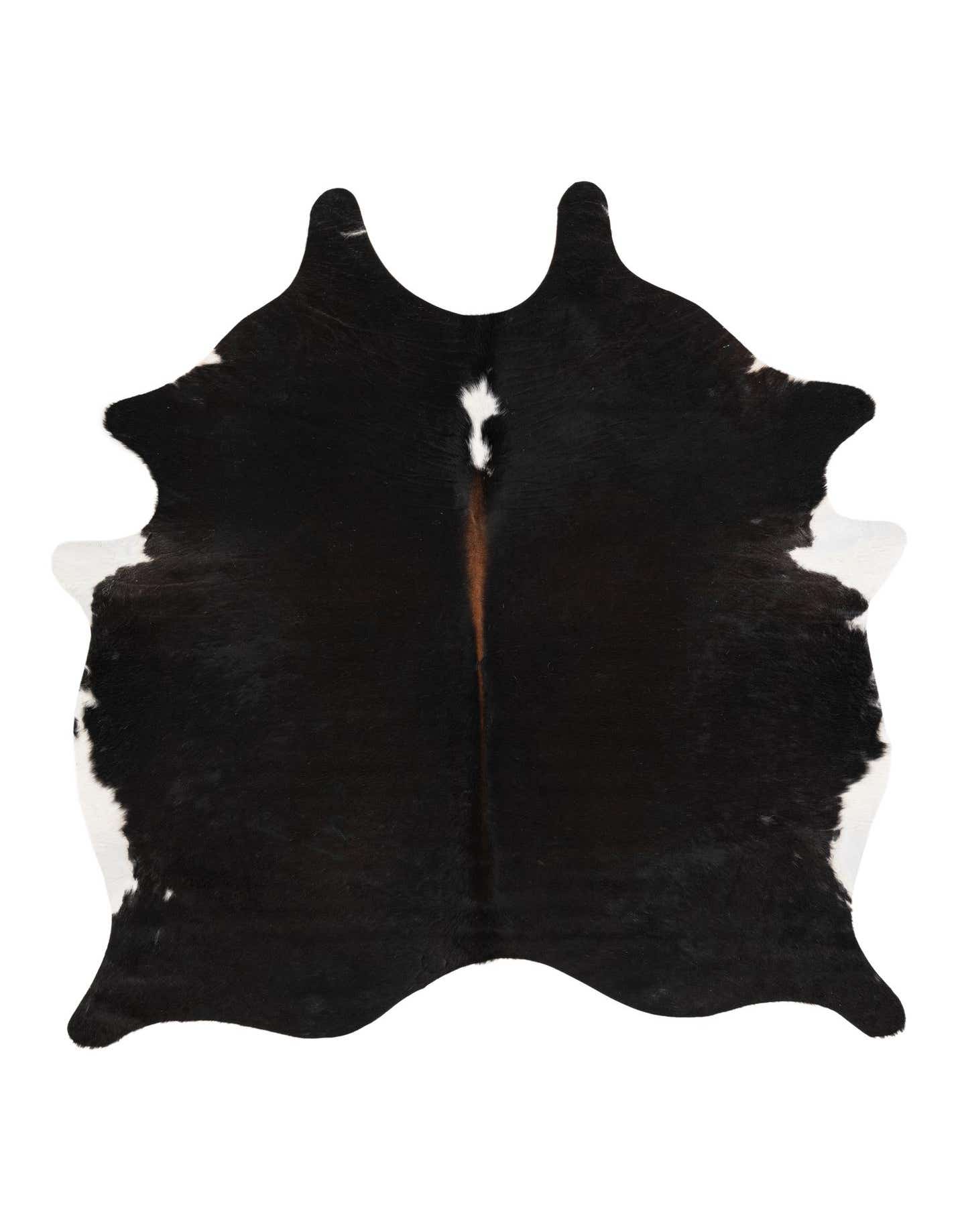 A 5' 10 x 6' 4 black and white cowhide rug with a natural, irregular shape, featuring a central brown stripe.