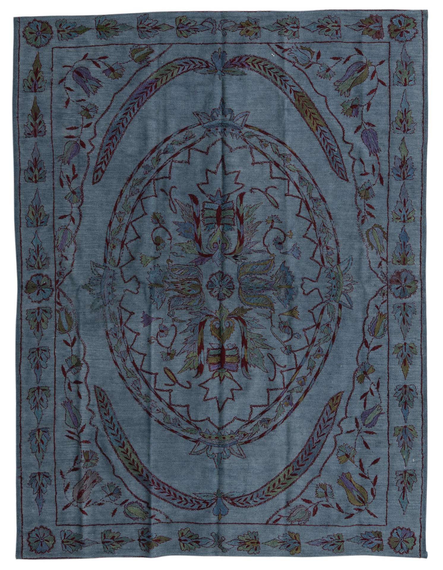 A 5x8 rectangular Kilim Suzani rug featuring a blue and gray background with a central floral medallion and tribal patterns in muted reds, greens, and purples.