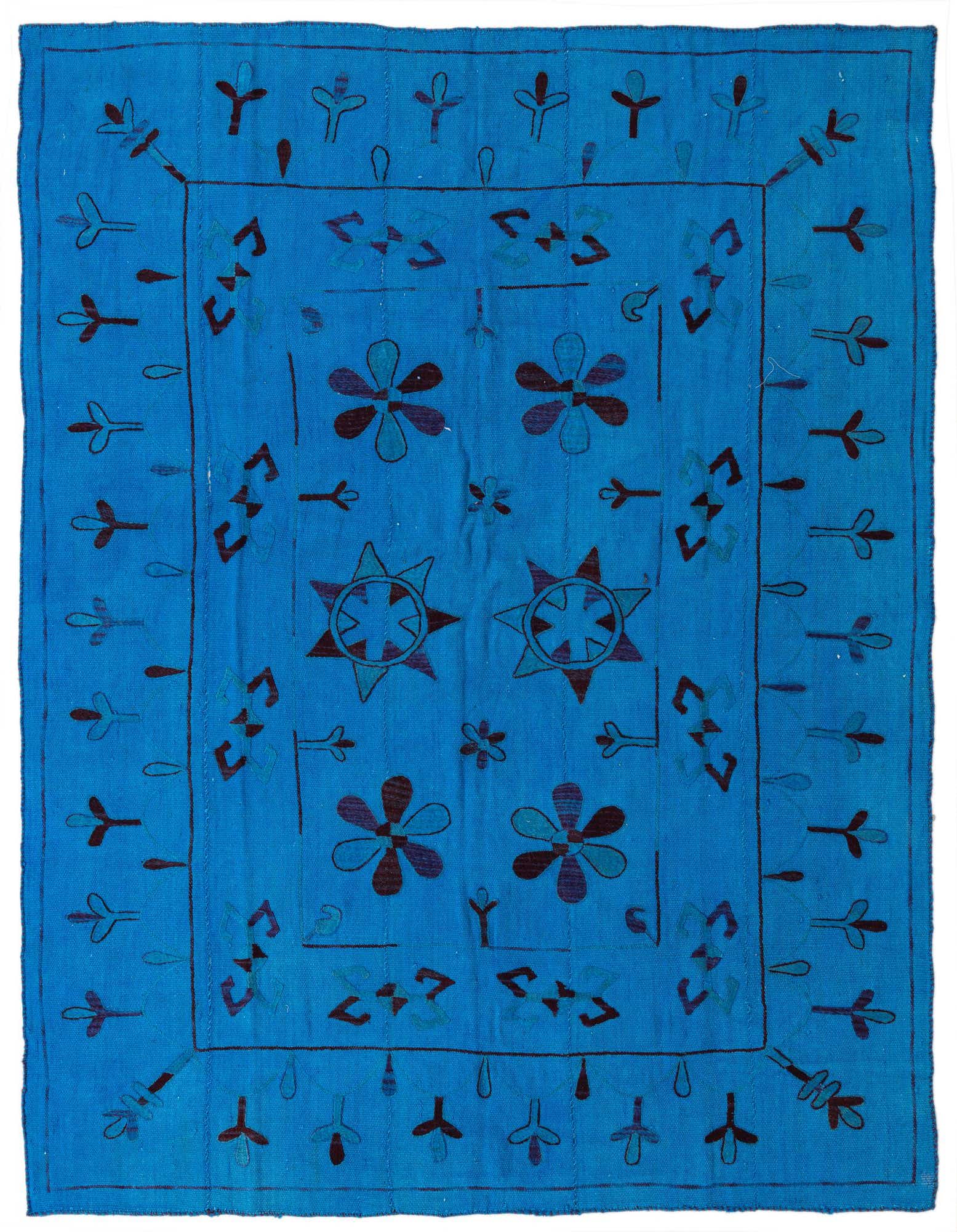 A 6x9 rectangular blue flatweave rug with a tribal abstract pattern featuring dark blue flowers, stars, and geometric shapes.
