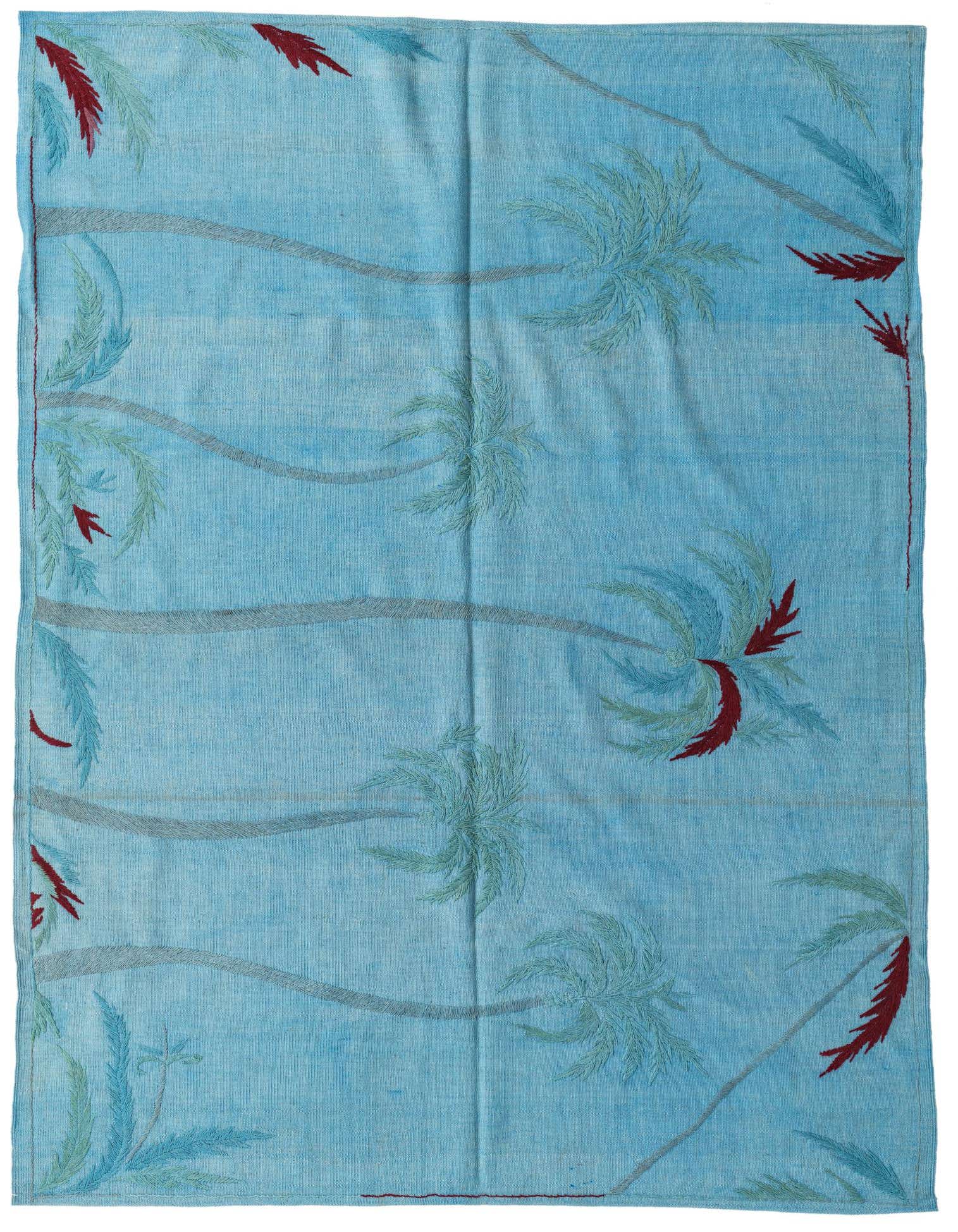 A 5x8 rectangular blue flatweave rug with a modern tribal pattern featuring light blue palm trees and red fronds.