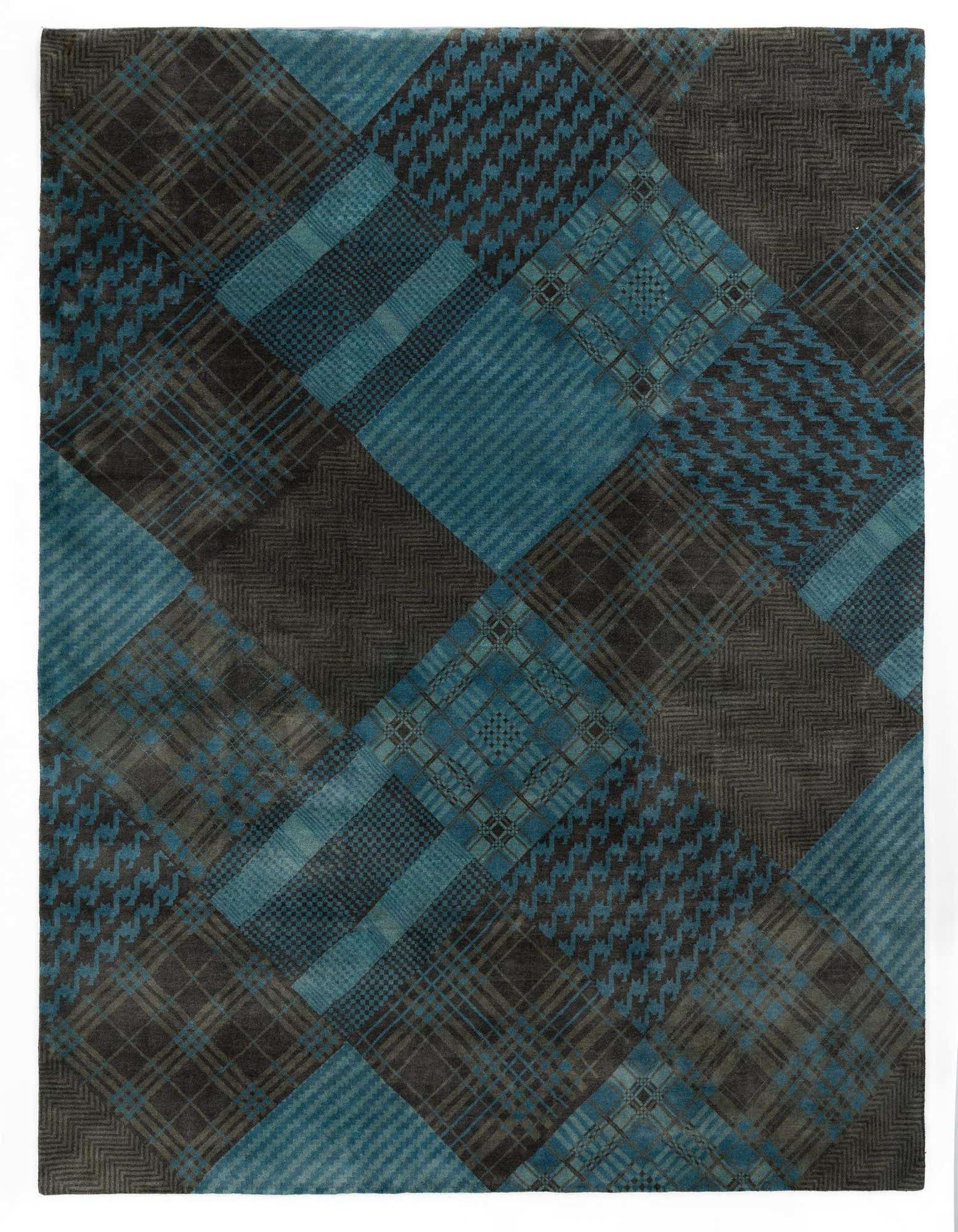 A rectangular 8x10 Modern Manshu rug featuring a patchwork of blue and dark gray plaid, houndstooth, and striped patterns, ideal for a living room.