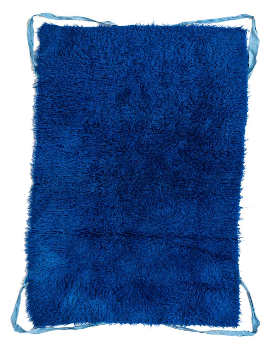 A vibrant 3x5 rectangular blue shag rug, handmade from wool, featuring a plush, textured pile and light blue trim.