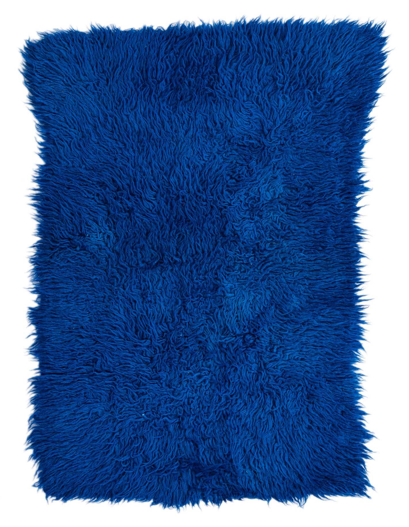 A rectangular 2x3 blue shag rug with a thick, plush pile, handmade from 100% wool.