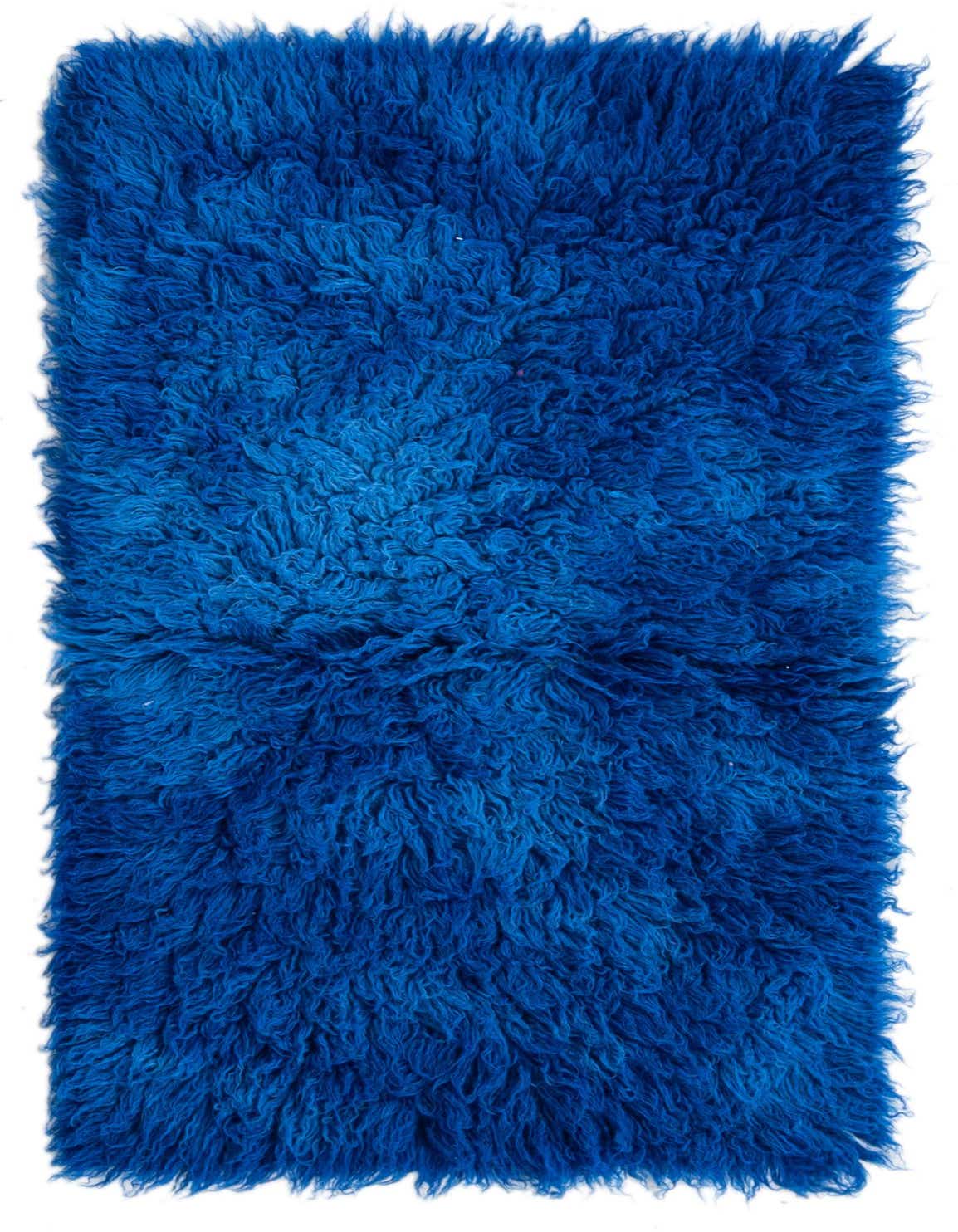 A rectangular 3x4 blue shag rug made of 100% wool, featuring a plush, textured pile in varying shades of blue.