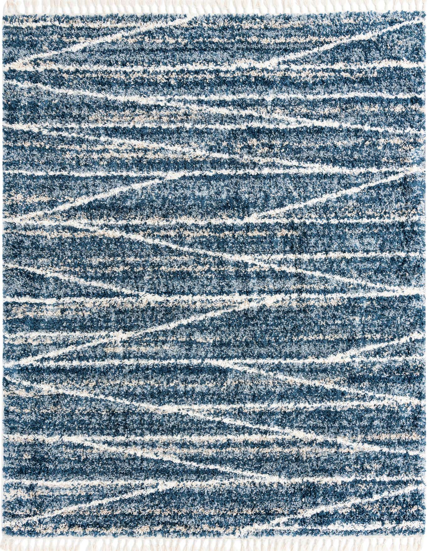 A 7x10 rectangular Serenity Shag rug in various shades of blue with abstract white and beige lines, featuring a plush pile and white fringe.