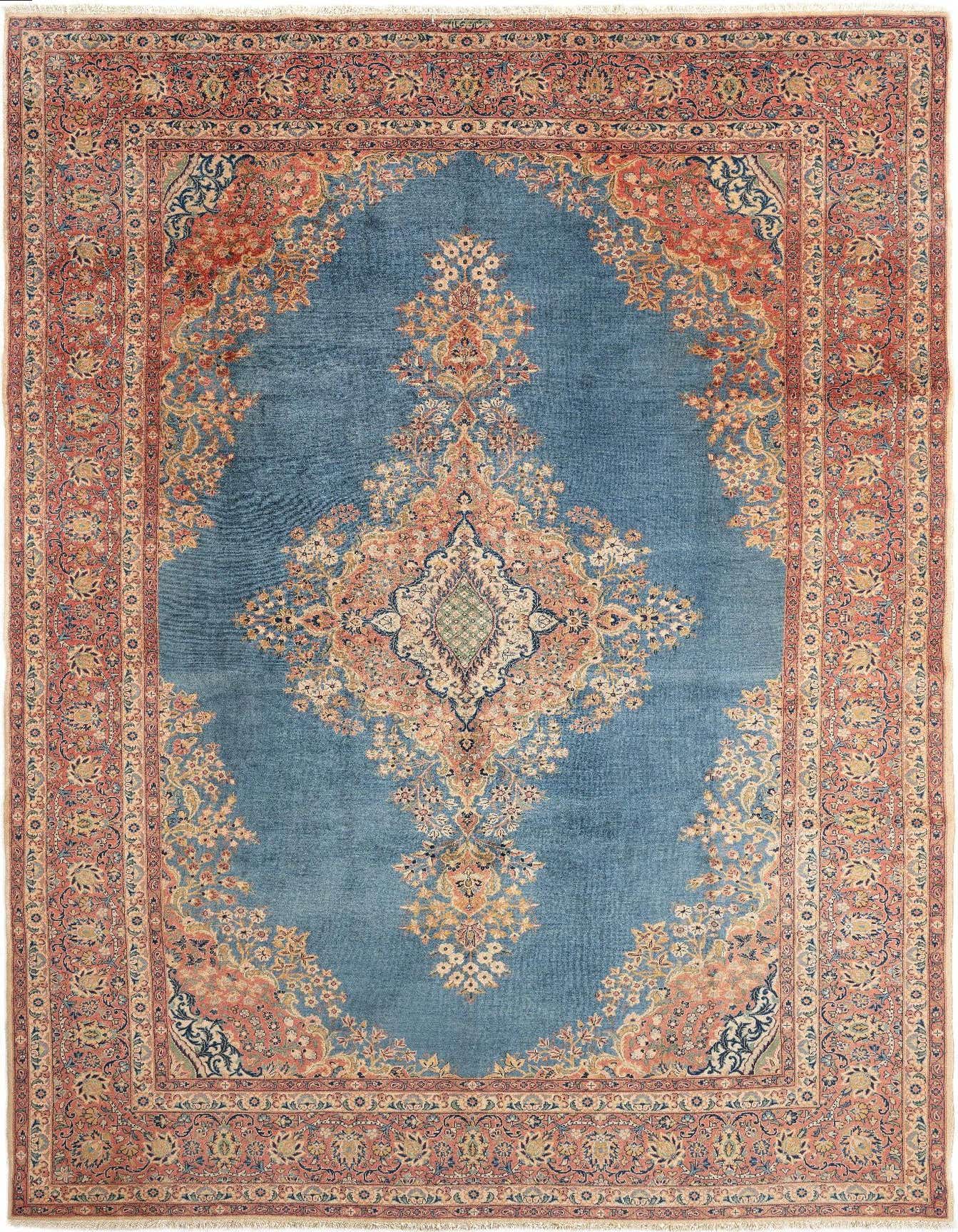 A rectangular handmade Persian rug featuring a central medallion on a blue field, surrounded by an intricate floral border in shades of red and blue.
