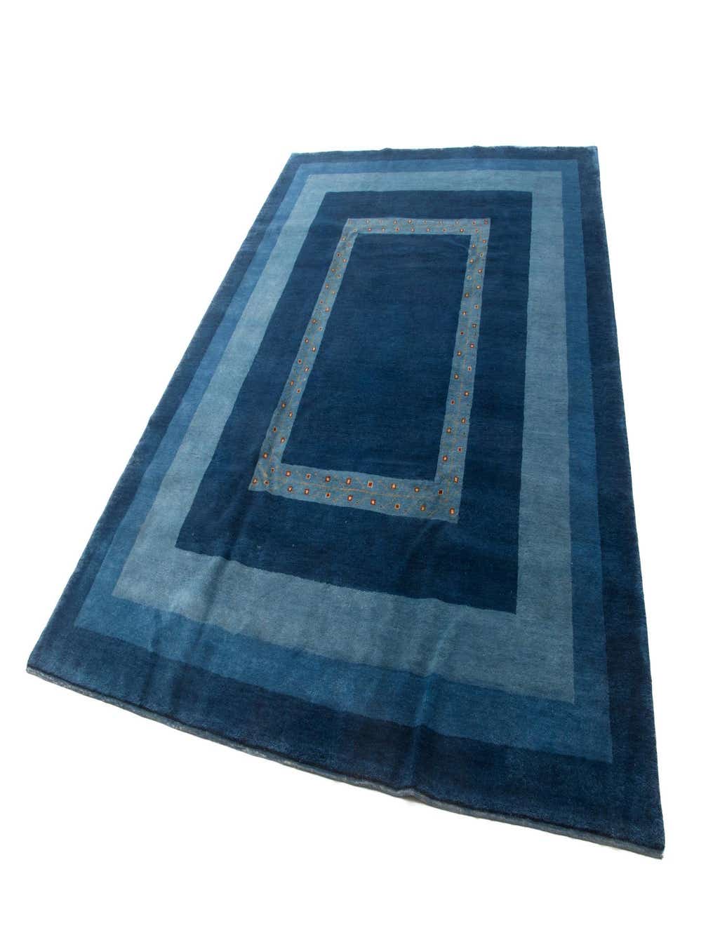 A 6x9 rectangular blue wool area rug with a concentric border design in varying shades of blue, featuring a dotted inner frame.
