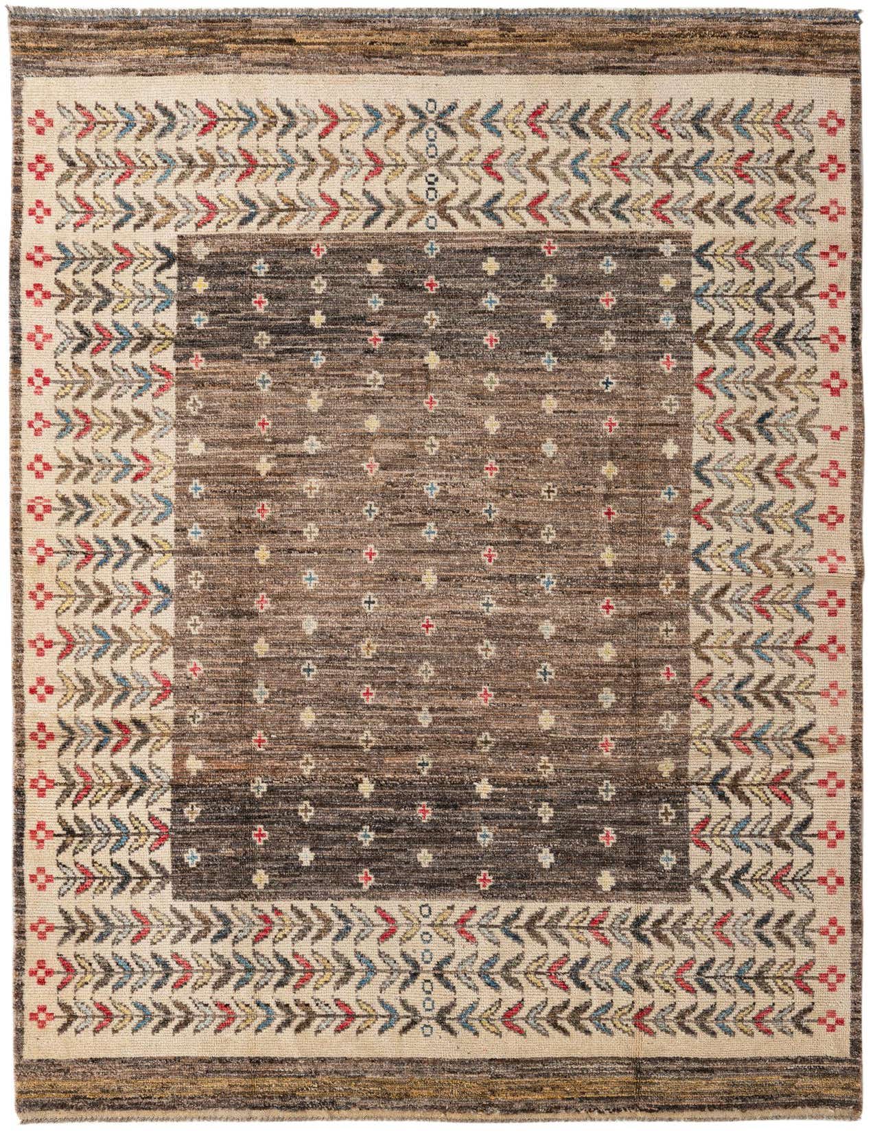 A 6x9 rectangular Ariana Ziegler wool rug featuring a brown abstract center with small colorful motifs, framed by a tan border with a vibrant leaf pattern.