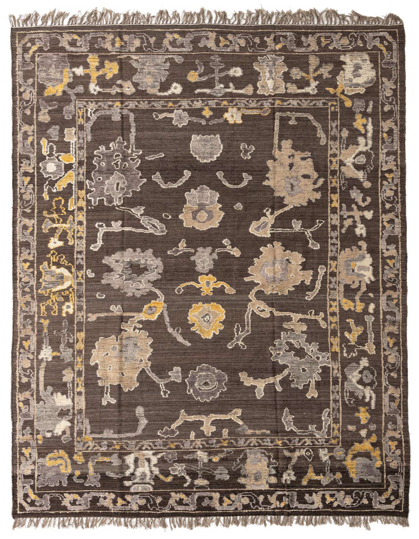 A 10x14 rectangular brown shag rug with a tribal-modern pattern in tan, grey, and yellow, featuring a distinct border and fringe.