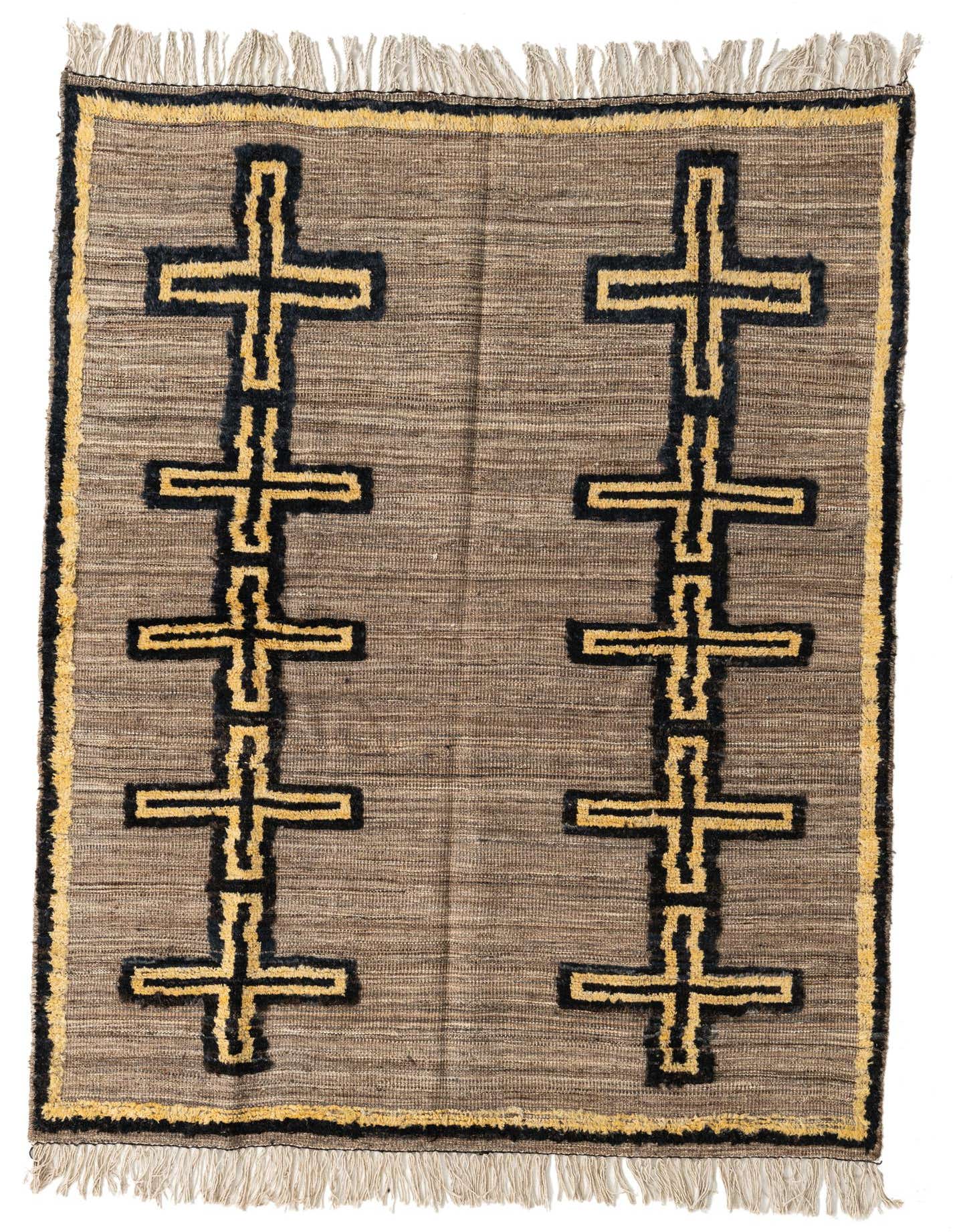 A 5x8 rectangular brown and tan wool rug with two vertical columns of black and gold tribal cross patterns, featuring shag pile and fringe.