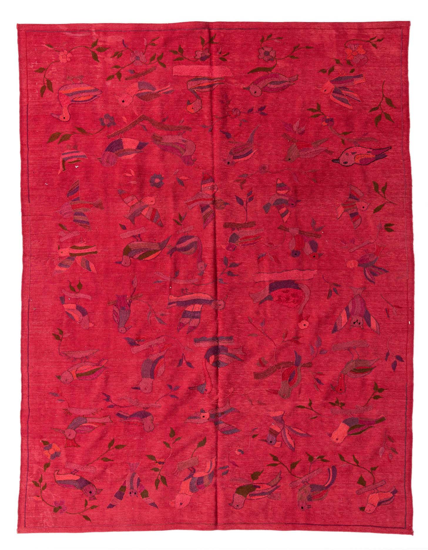 A 7x10 rectangular red wool flatweave rug with a vibrant tribal bird and floral pattern, suitable for a living room.