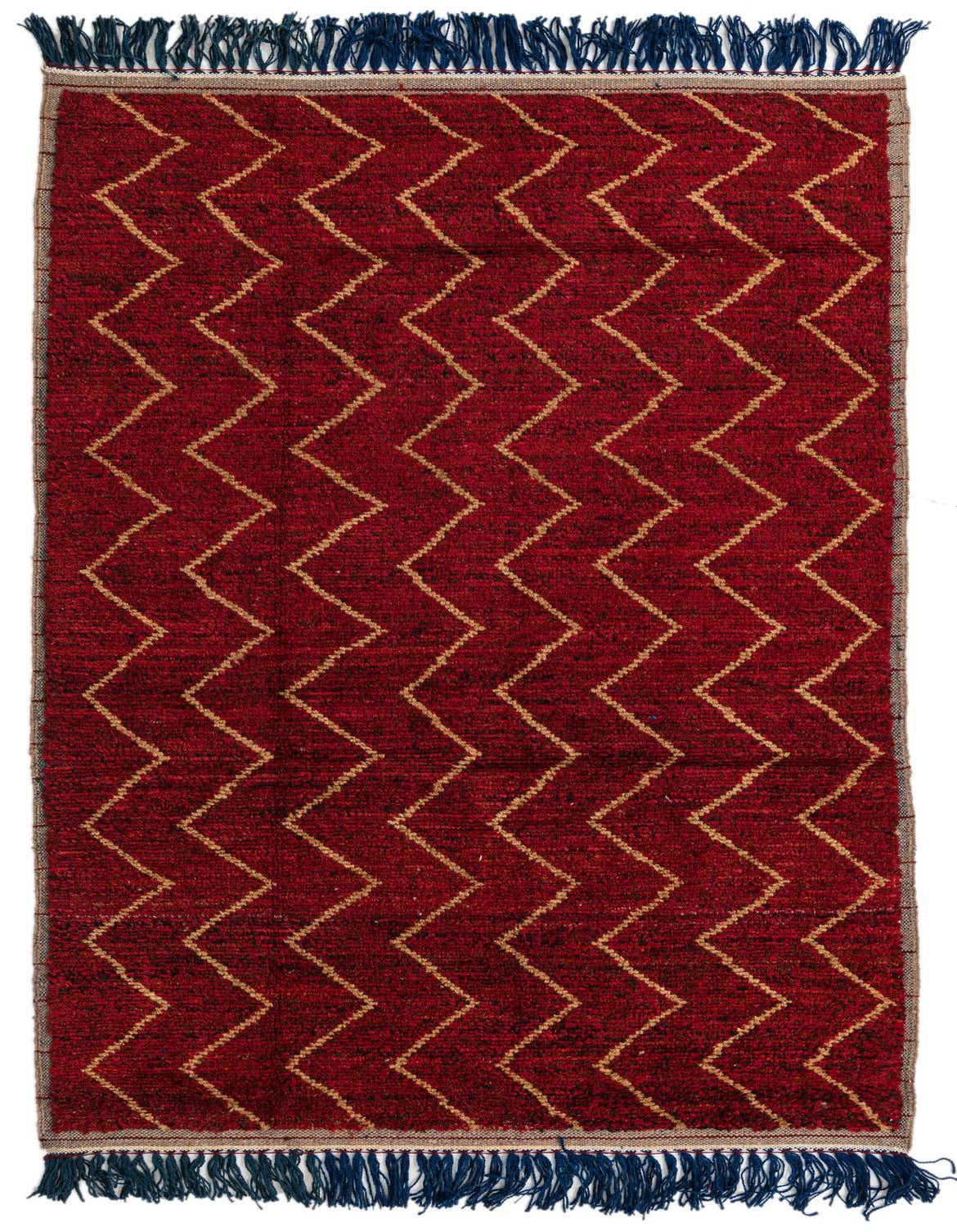 A 5x8 rectangular red wool shag rug with a repeating gold zigzag tribal pattern and dark blue fringe.