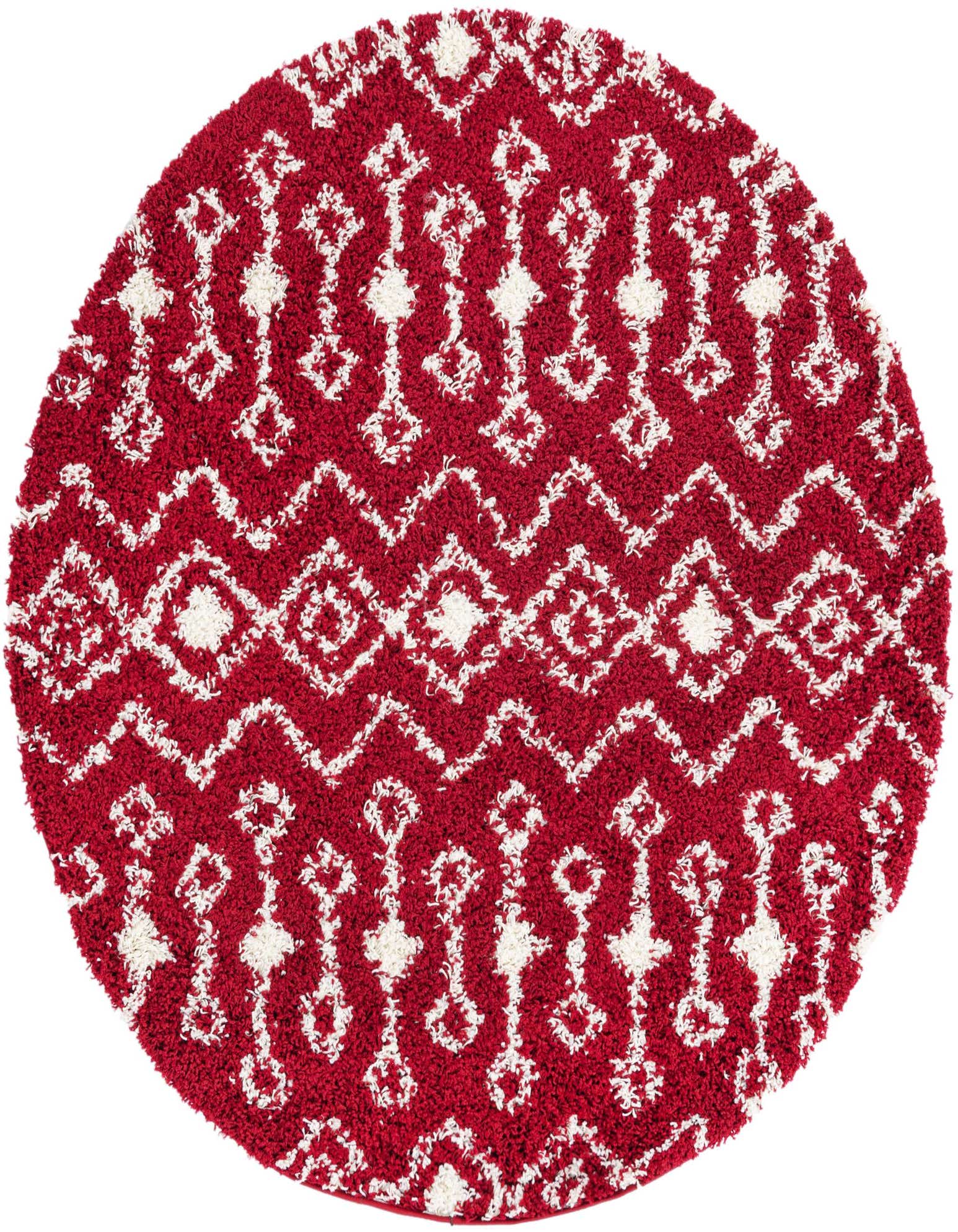 A round red shag rug with a white tribal pattern, featuring diamonds and zigzags, on a white background.