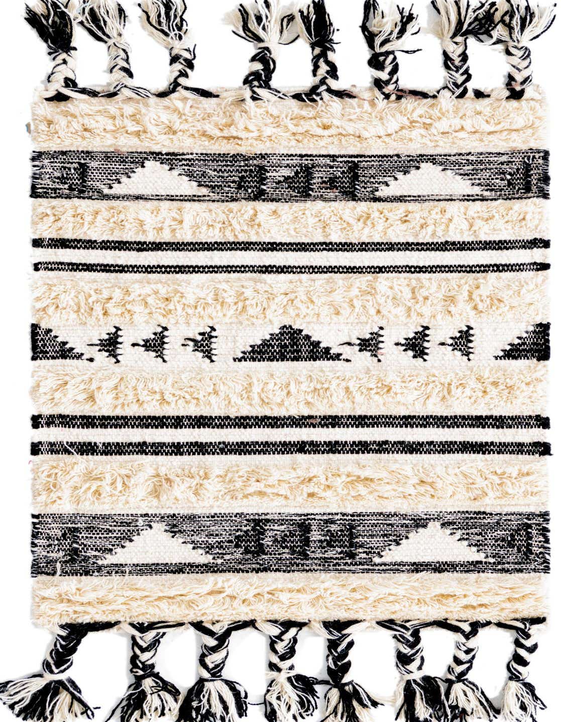 A 2x3 rectangular black and cream tribal shag rug with braided tassels, featuring geometric patterns and textured stripes.