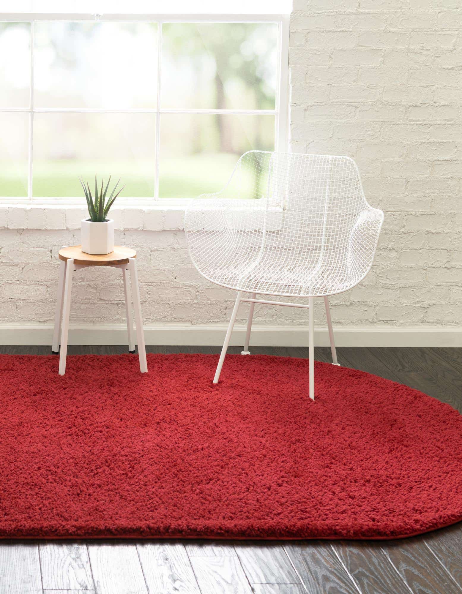 A plush, oval 3' 3 x 5' 3 red shag rug with a textured pile, perfect for adding warmth to any indoor space.