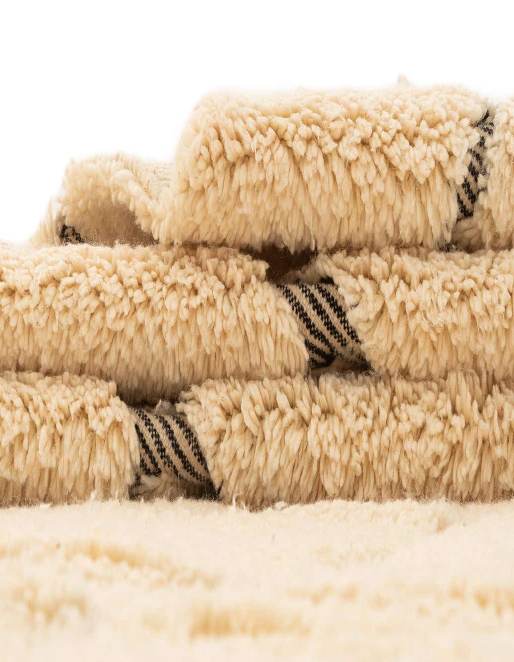 Close-up of a plush, ivory wool rug with a medium pile, showing its soft texture and handmade quality.