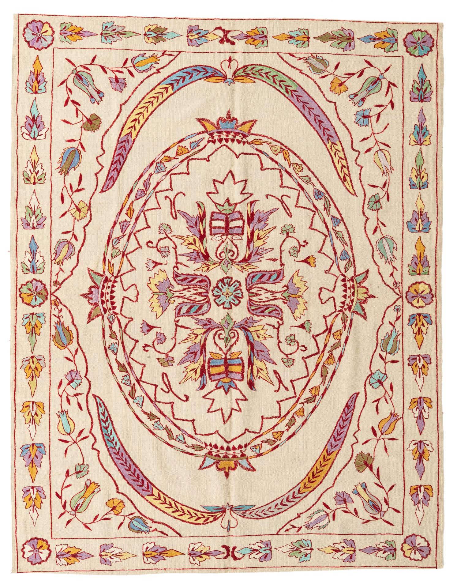 A 6x9 rectangular ivory wool flatweave rug with a colorful tribal medallion and floral border.