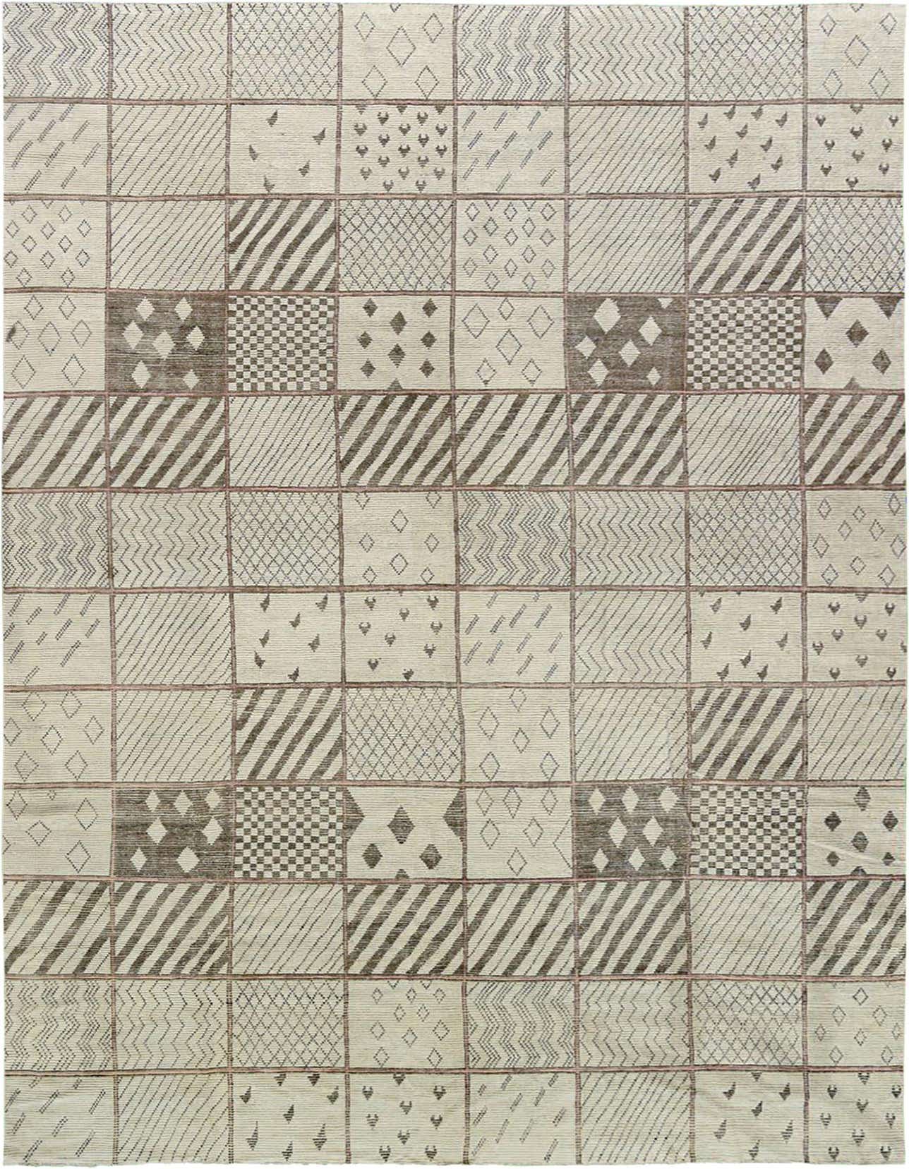 A rectangular ivory and cream wool shag rug with a modern tribal patchwork pattern, featuring various geometric designs in each square.