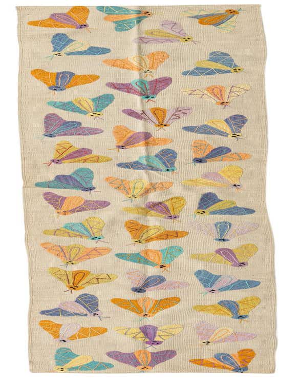 A 9 ft runner rug with a cream background, featuring colorful embroidered moths in shades of blue, orange, purple, and yellow, perfect for a hallway.