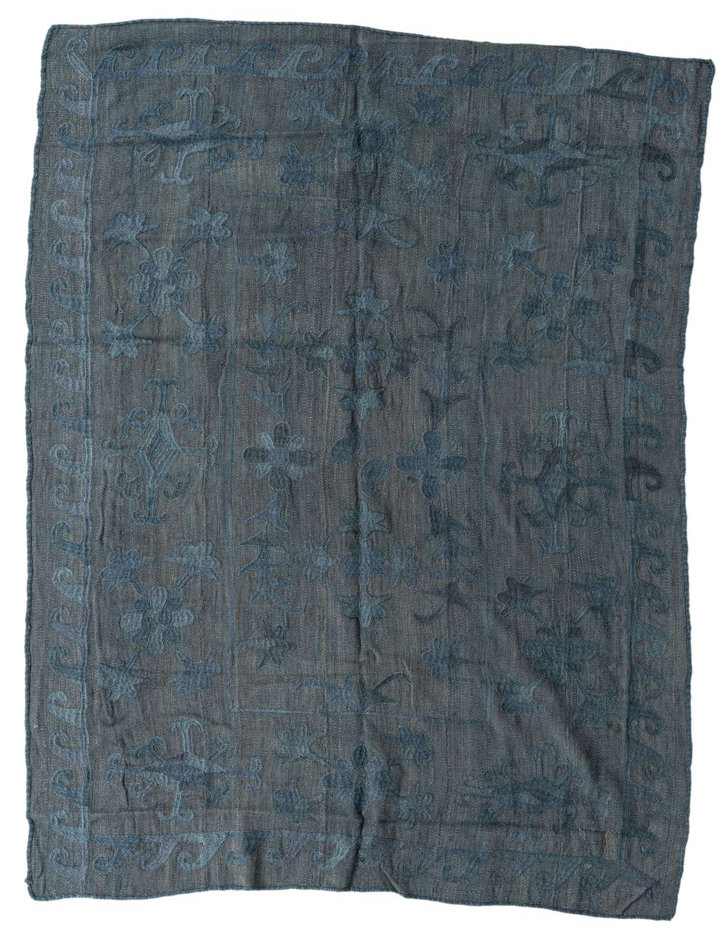 A 5x8 rectangular gray flatweave wool rug with a subtle tribal and floral pattern, suitable for a living room.