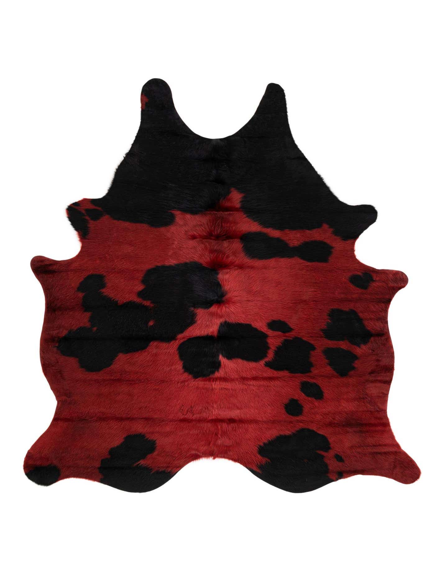 A vibrant red and black cowhide rug with an irregular, natural shape, featuring bold black spots on a rich red background.