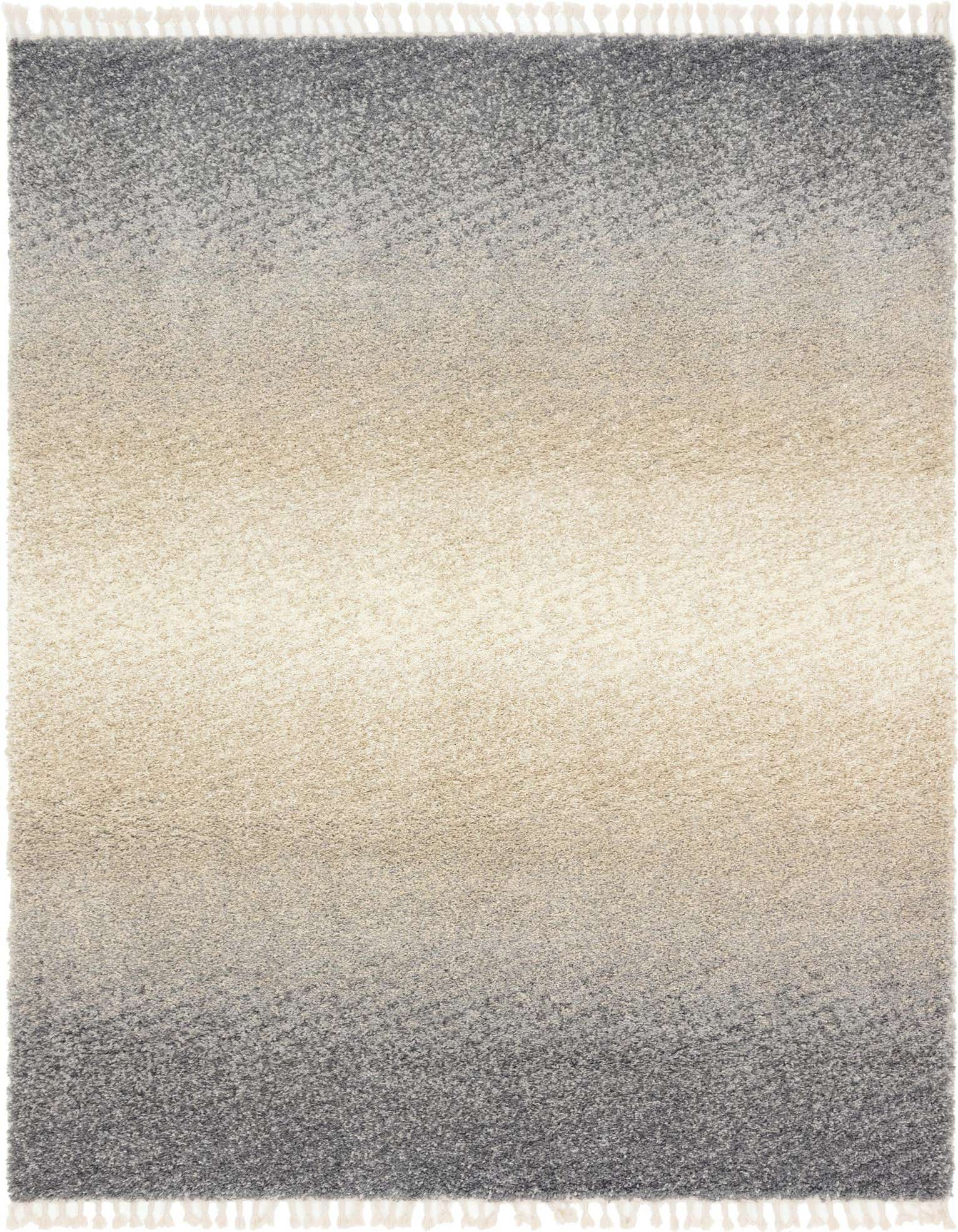 A rectangular 8x10 gray and silver shag rug with a modern, abstract ombre fade from dark gray to light silver, featuring decorative tassels.