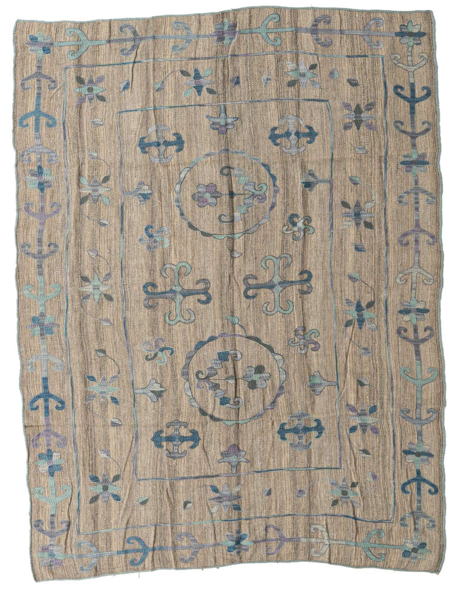 A 6x9 rectangular gray wool flatweave rug with a tribal Suzani pattern in muted blue, purple, and teal.